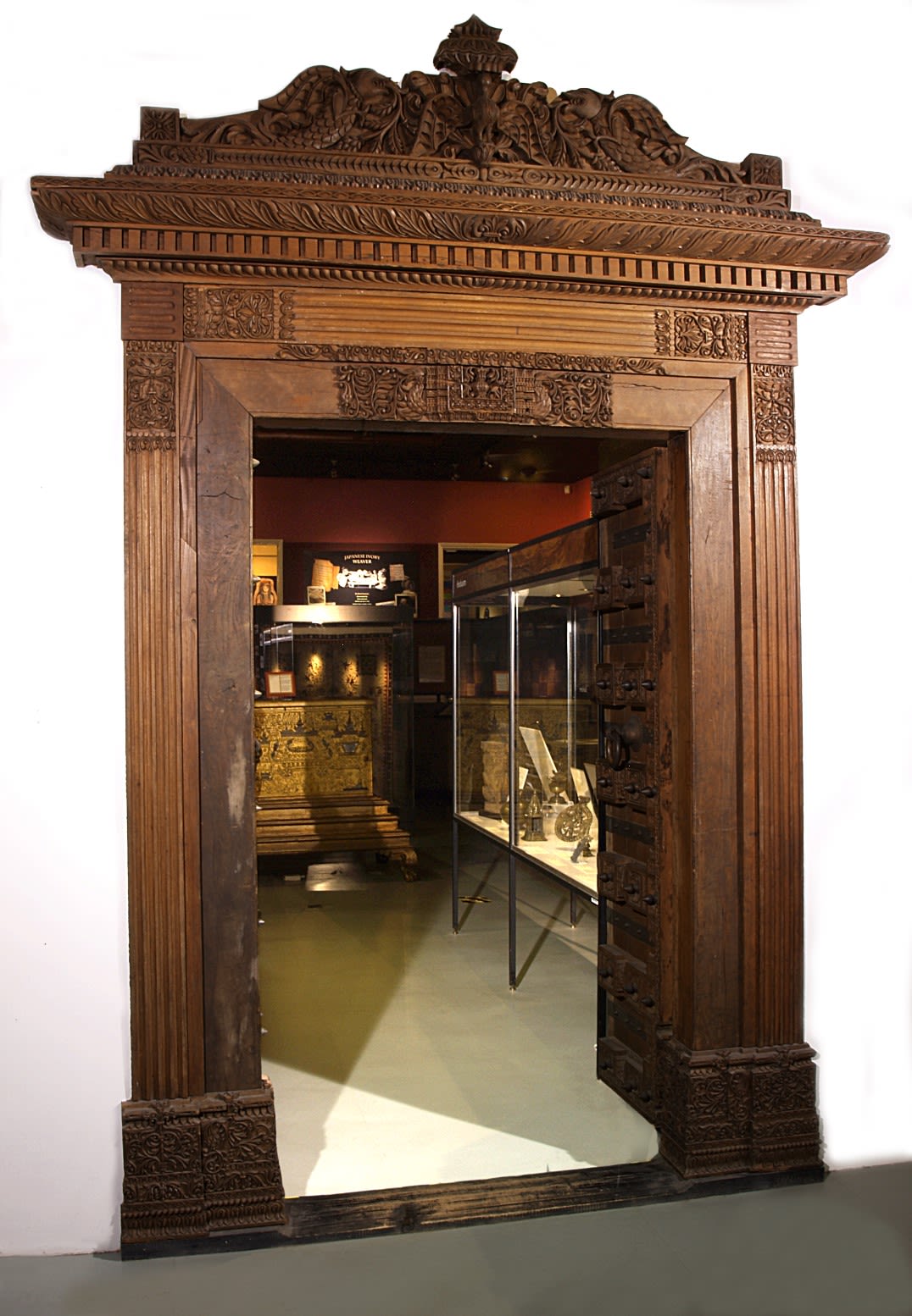 Carved wooden archway. The door is open, but we can see the door itself has black decorations and a large circular door handle.