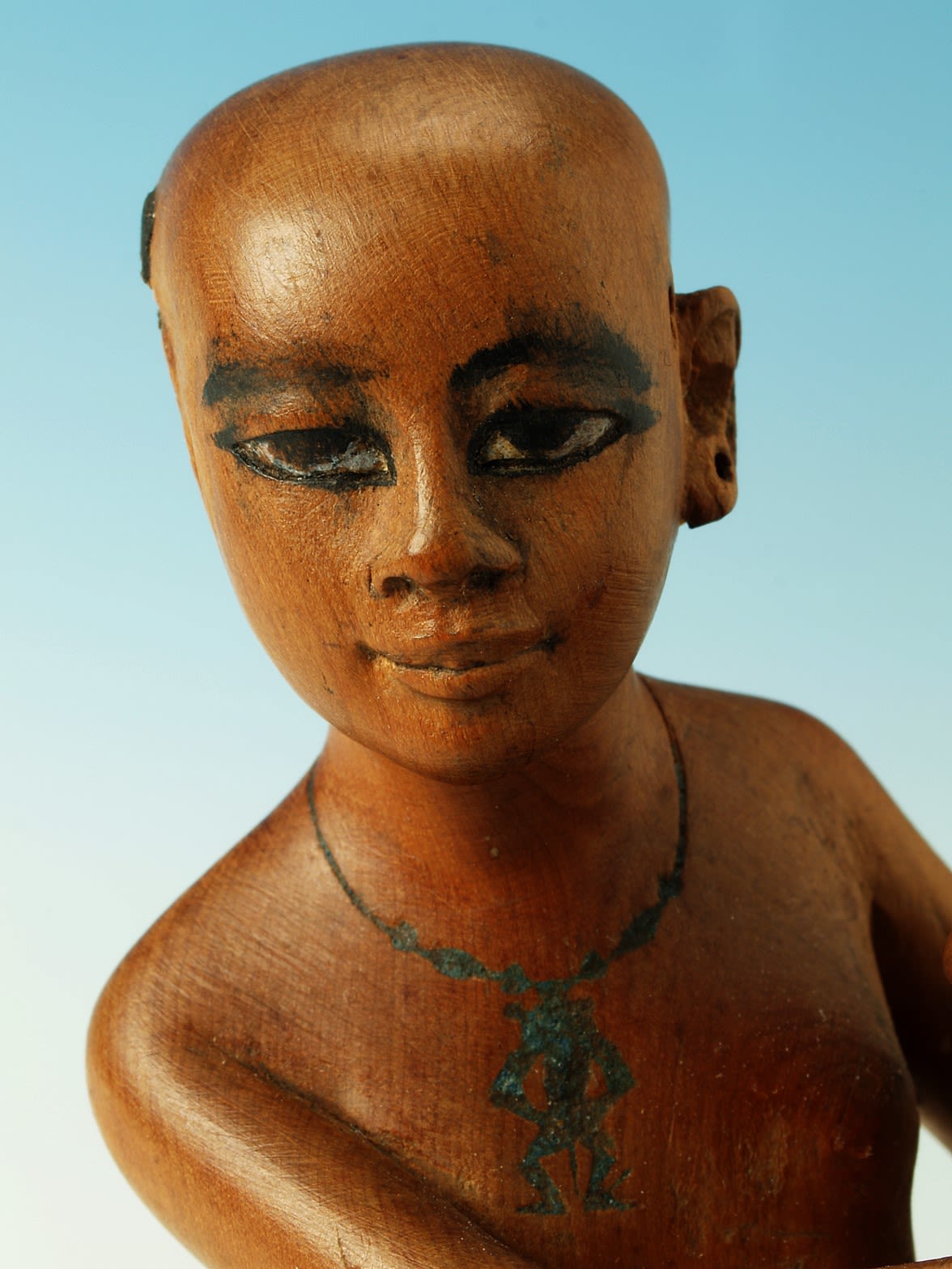 Close up on the face of the servant girl statue. The grain of the wood is visible and the girl bears a relaxed expression.