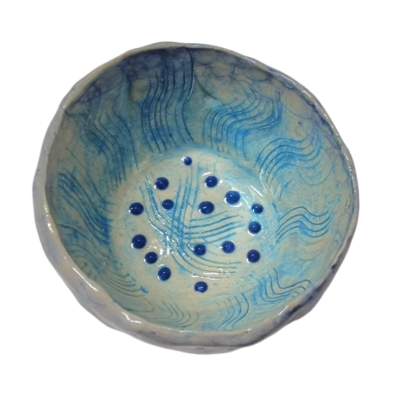 Above view of hump made stoneware bowl with abstract blue scratched lines and dark blue dots
