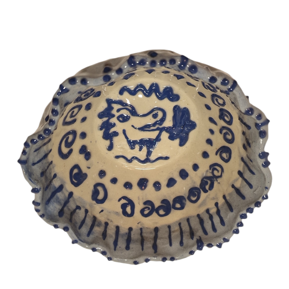 Above view of hump made stoneware bowl with blue dragon like creature in the center surrounded by dots and swirls