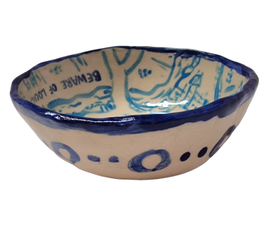 Side view of hump made stoneware bowl with blue rim and blue shapes on side