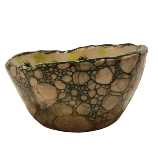 Side view of hump made stoneware bowl with dark green bubble paint pattern
