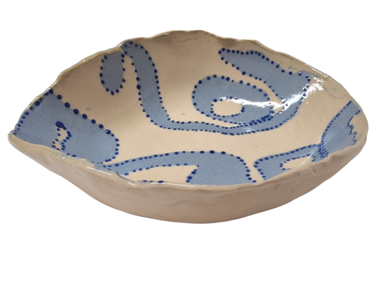 Above view of hump made stoneware bowl with abstract blue swirls and dots