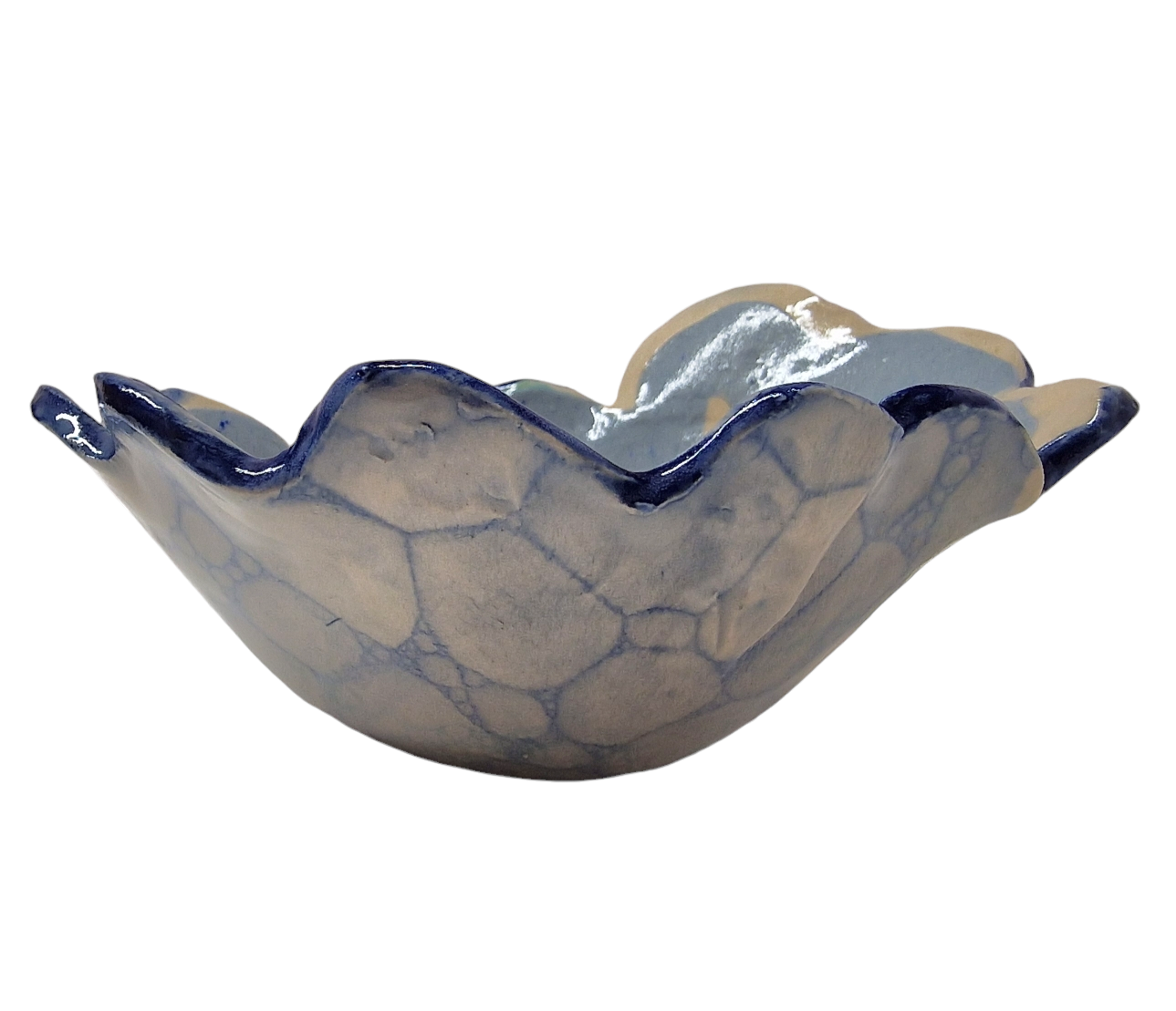 Side view of hump made stoneware bowl with blue bubble paint pattern and wave like carved rim