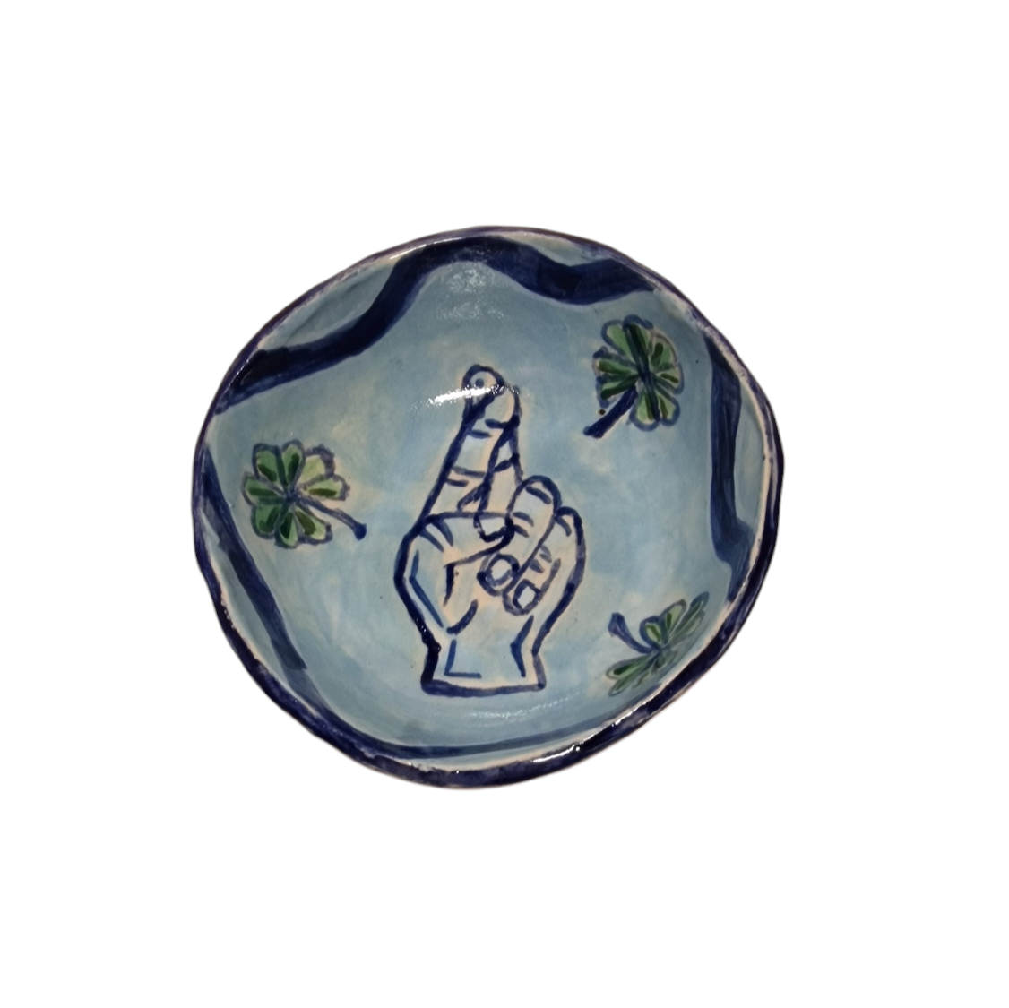 Above view of hump made stoneware bowl with blue illustration of a hand with its fingers crossed and three green four leaf clovers