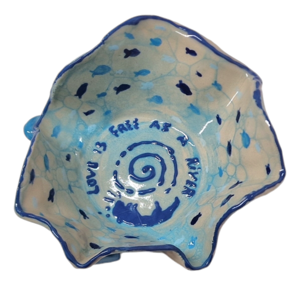 Above view of hump made stoneware bowl with blue bubble pattern and small fish. In the center we see and otter and the text reads: LOVE IS A FREE AS A RIVER