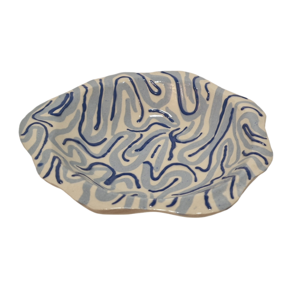 Above view of hump made stoneware shallow bowl with light and dark blue swirling lines
