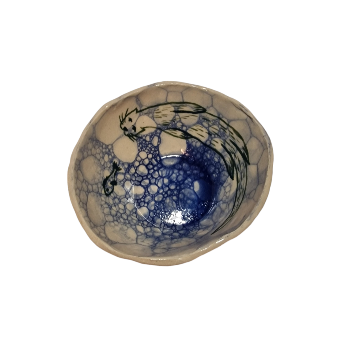 Above view of hump made stoneware bowl with blue bubble pattern and green illustrated otter and fish inside