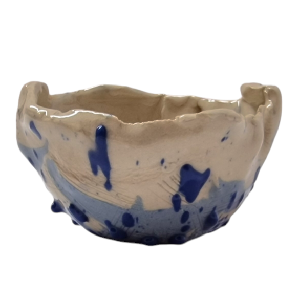 Side view of hump made stoneware bowl with blue abstract pattern and scratch marks