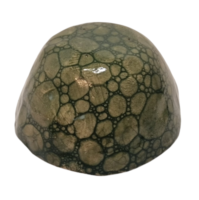 Side view of hump made stoneware bowl with dark green bubble paint pattern