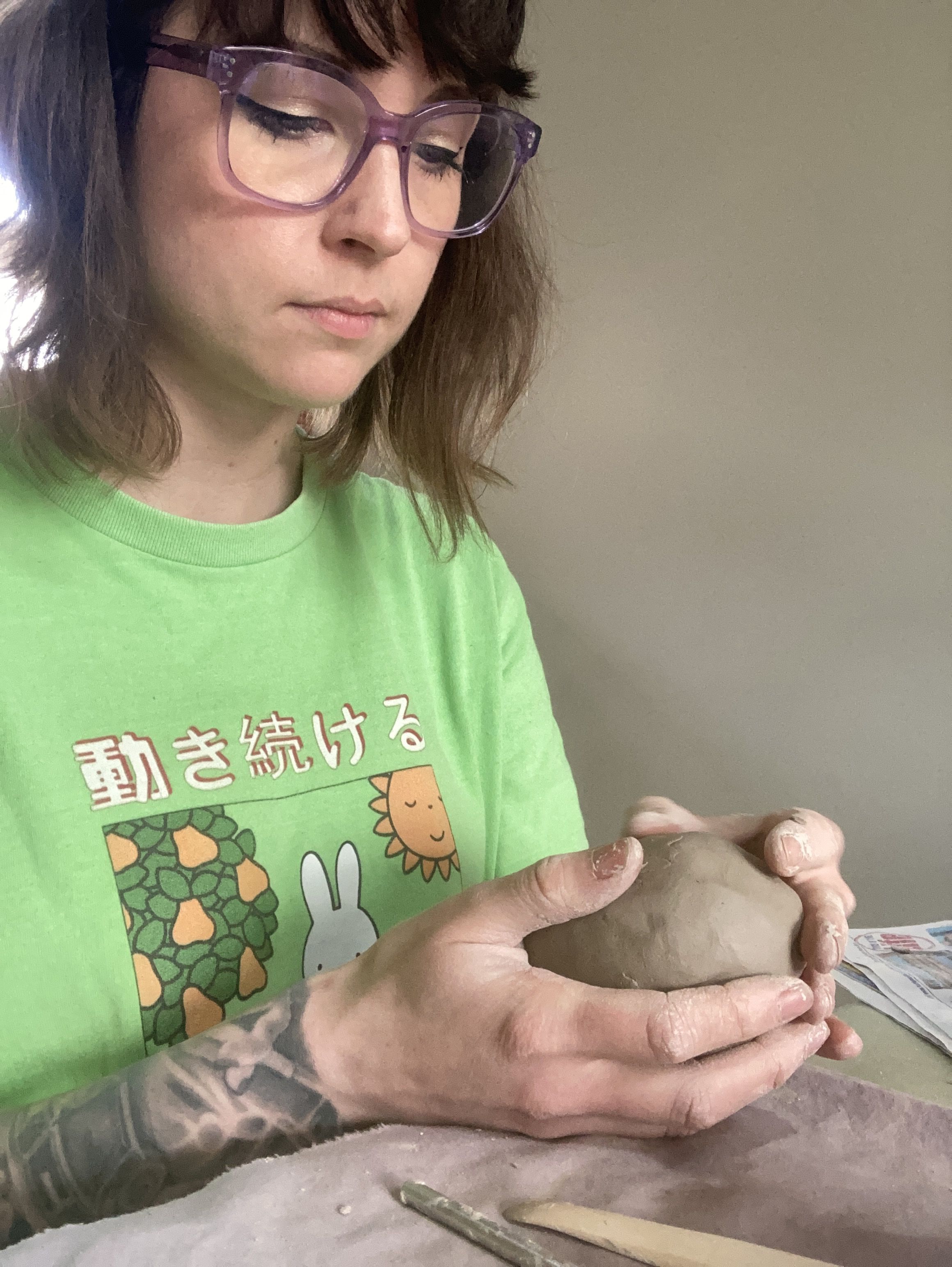 Photo of local artist Ruth Flowers. Ruth holds a ball of clay in her hands.