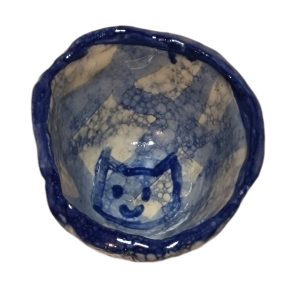 Above view of hump made stoneware bowl with blue bubble pattern and cat like face in center