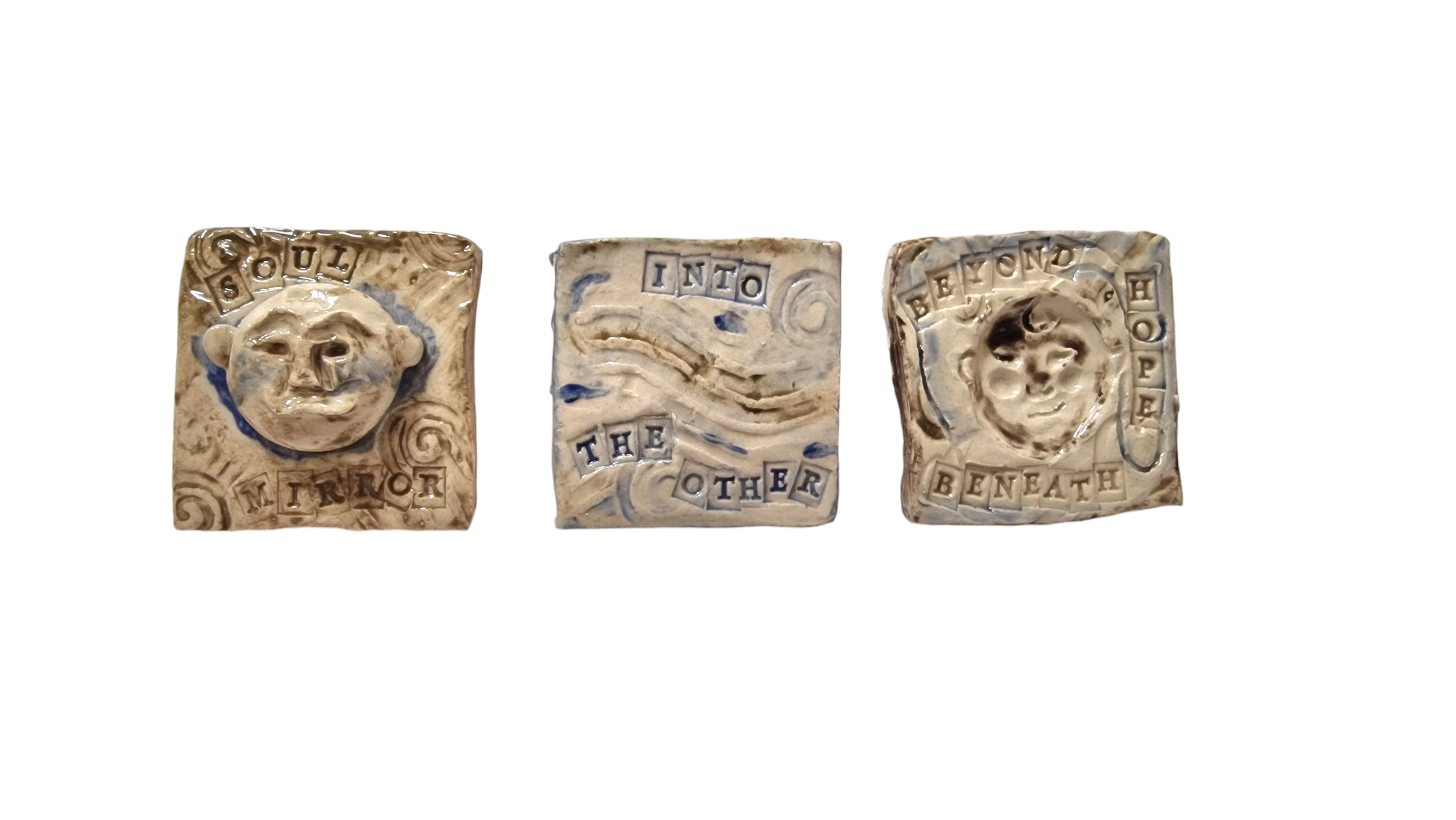 Three square tiles showing imprinted faces and abstract shapes. Text on the tiles reads soul, mirror, into, the other, beyond, hope, beneath