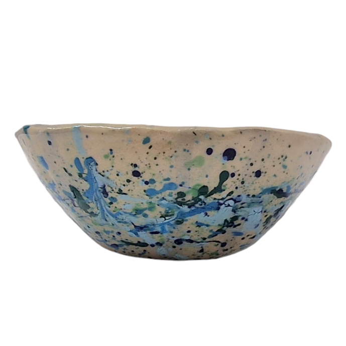 Side view of hump made stoneware bowl with green and blue splatter pattern