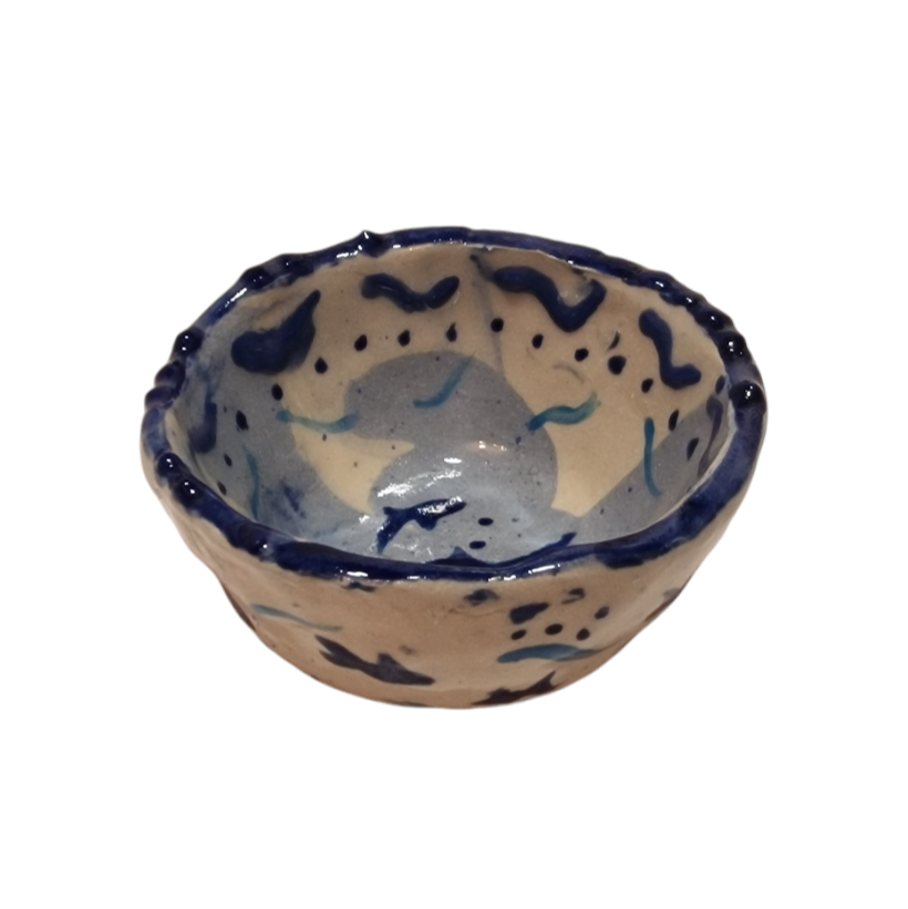 Above view of hump made stoneware bowl with abstract fish like blue shapes 