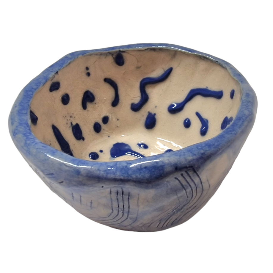 Side view of hump made stoneware bowl with blue scratch pattern on outside and blue dots on the inside