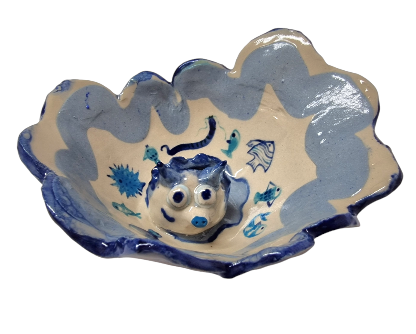 Above view of hump made stoneware bowl with 3D sculpted head of an animal. Surrounded by blue illustrations of fish and other water creatures.