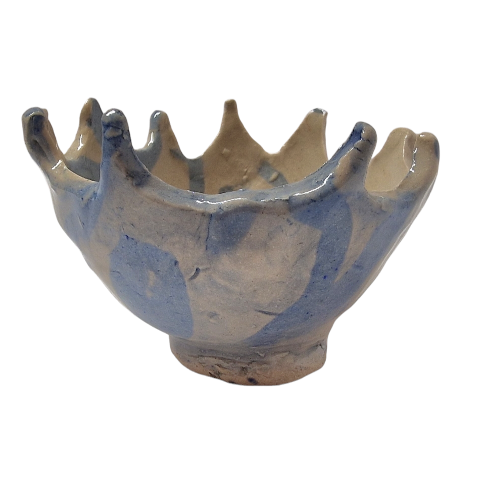 Side view of hump made stoneware bowl with blue pattern and wave like carved rim