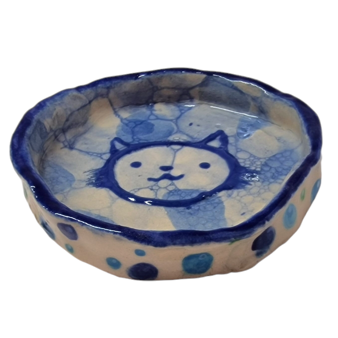 Above view of hump made stoneware bowl with blue bubble pattern and outline of a cat like face