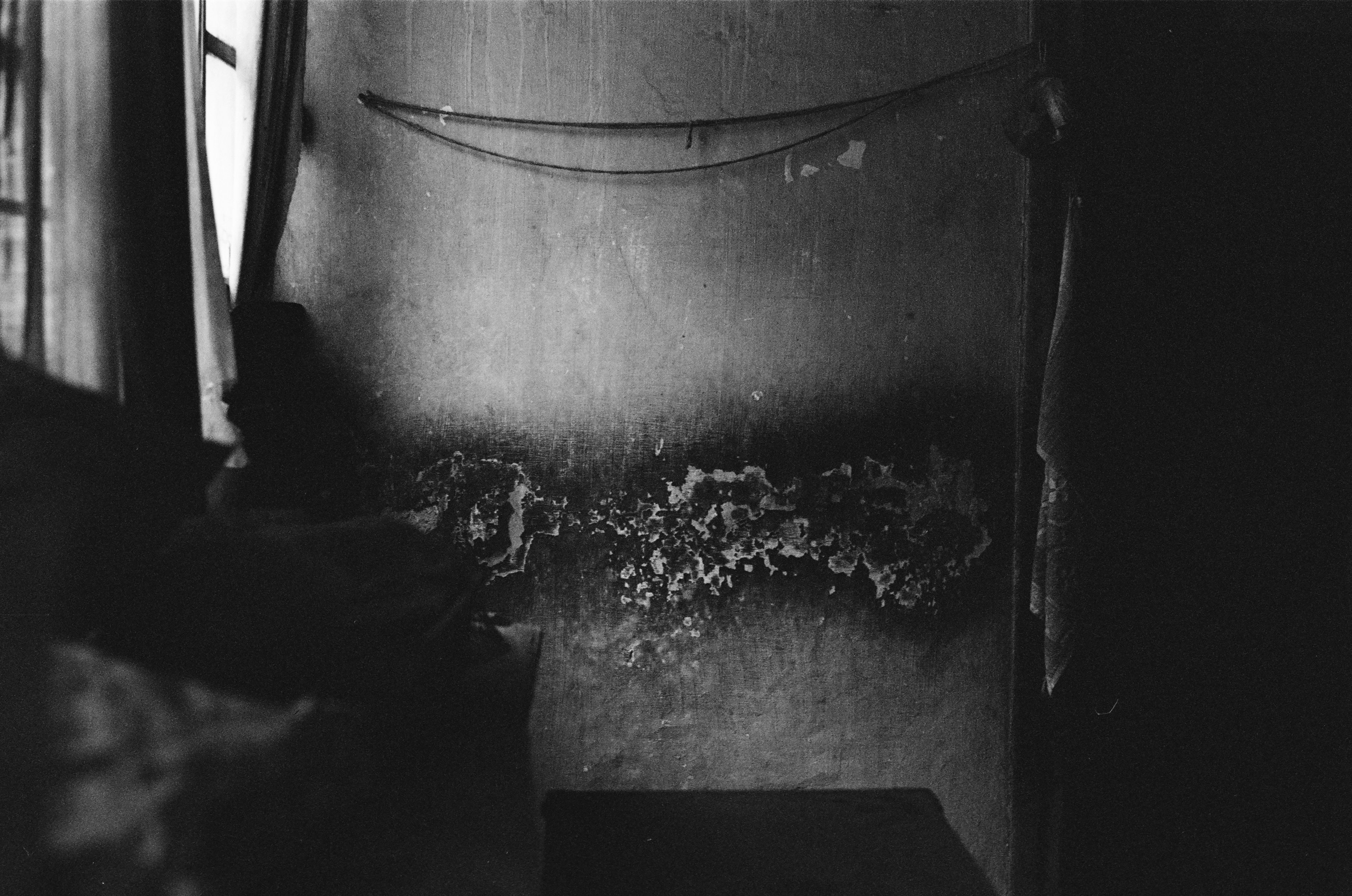 Black and white photo of a room showing decaying wall