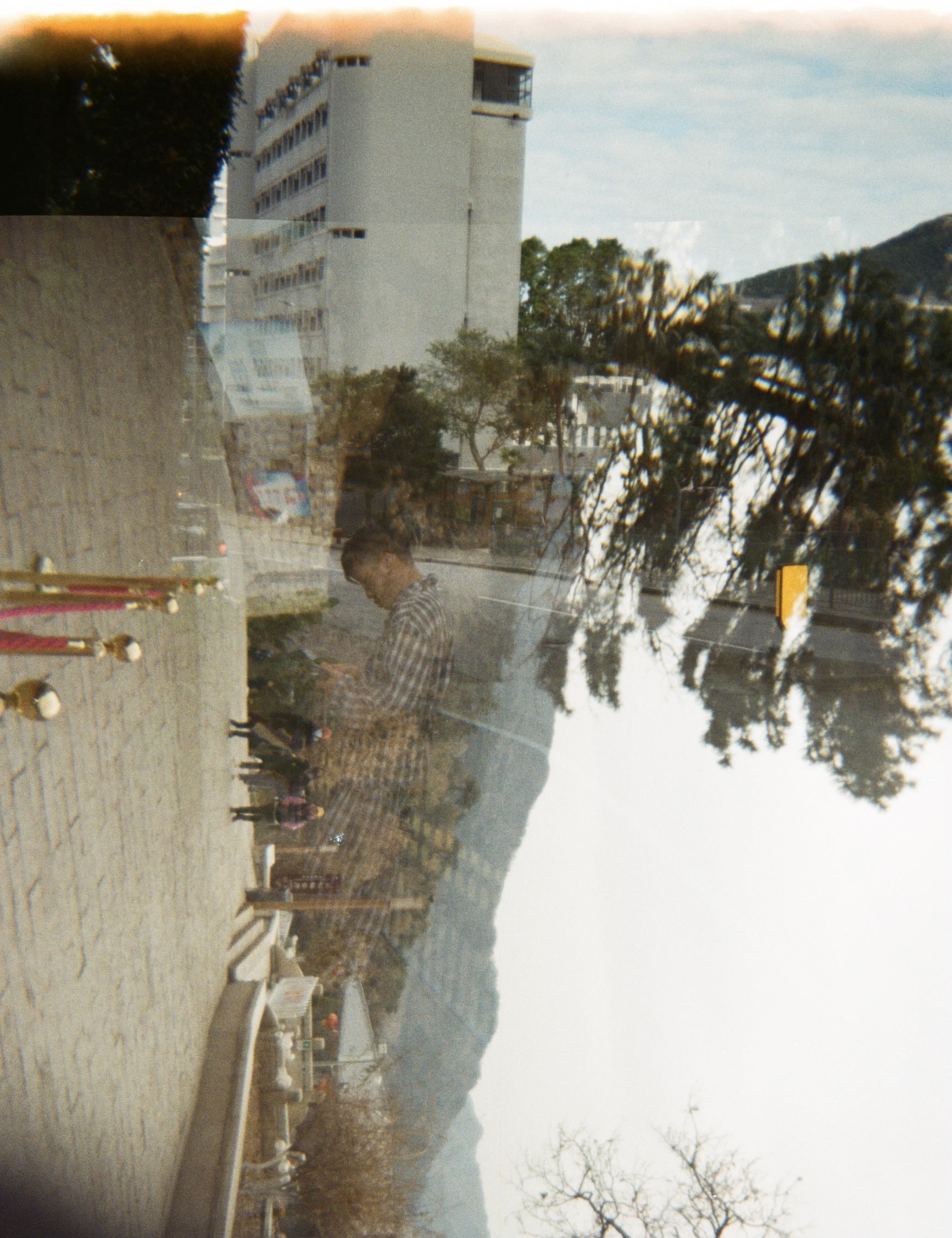 Double exposure photo showing a building and person in one image, overlayed with an image of mountains and trees