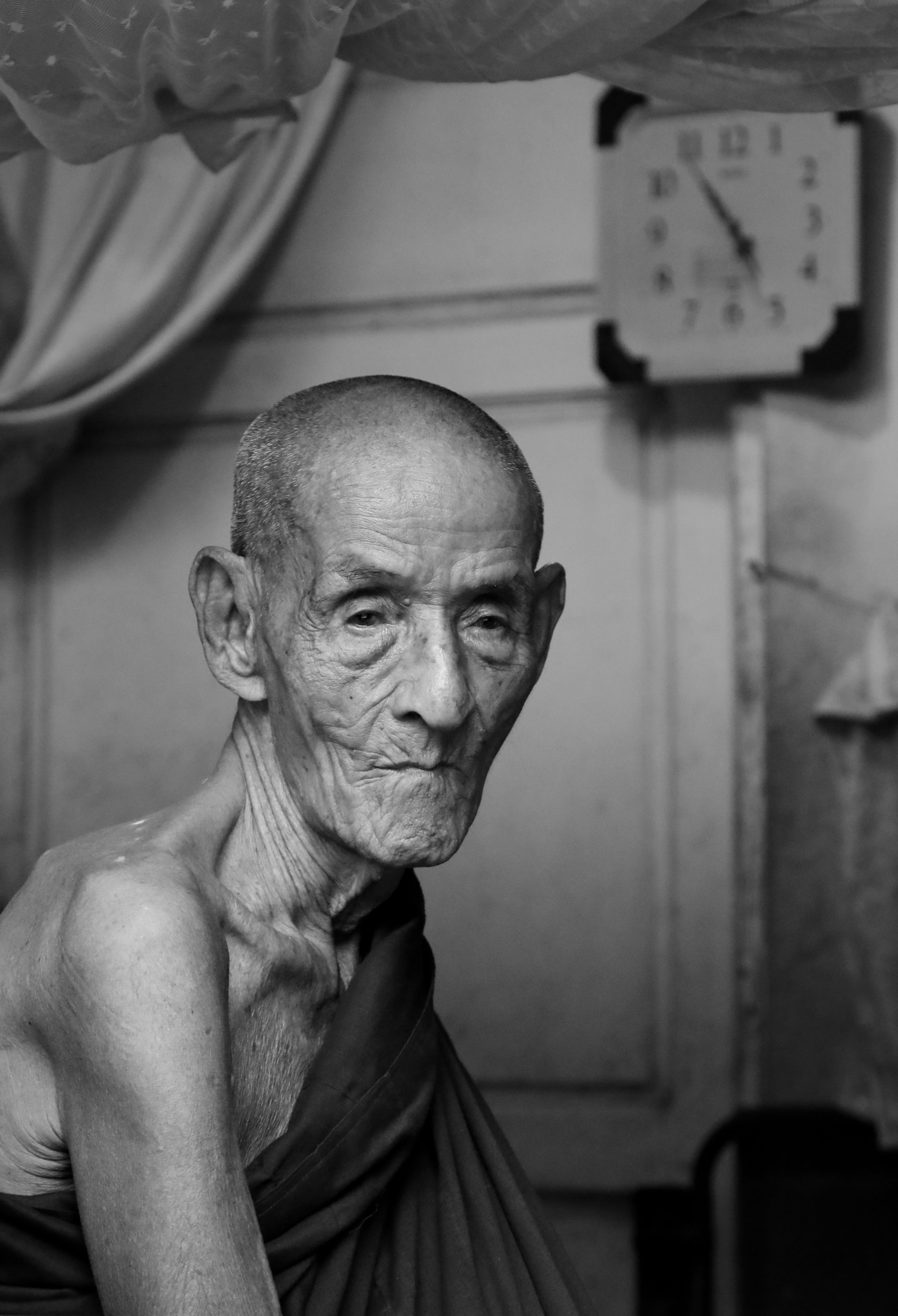 Black and white photo of a Buddhist monk sitting in their room.