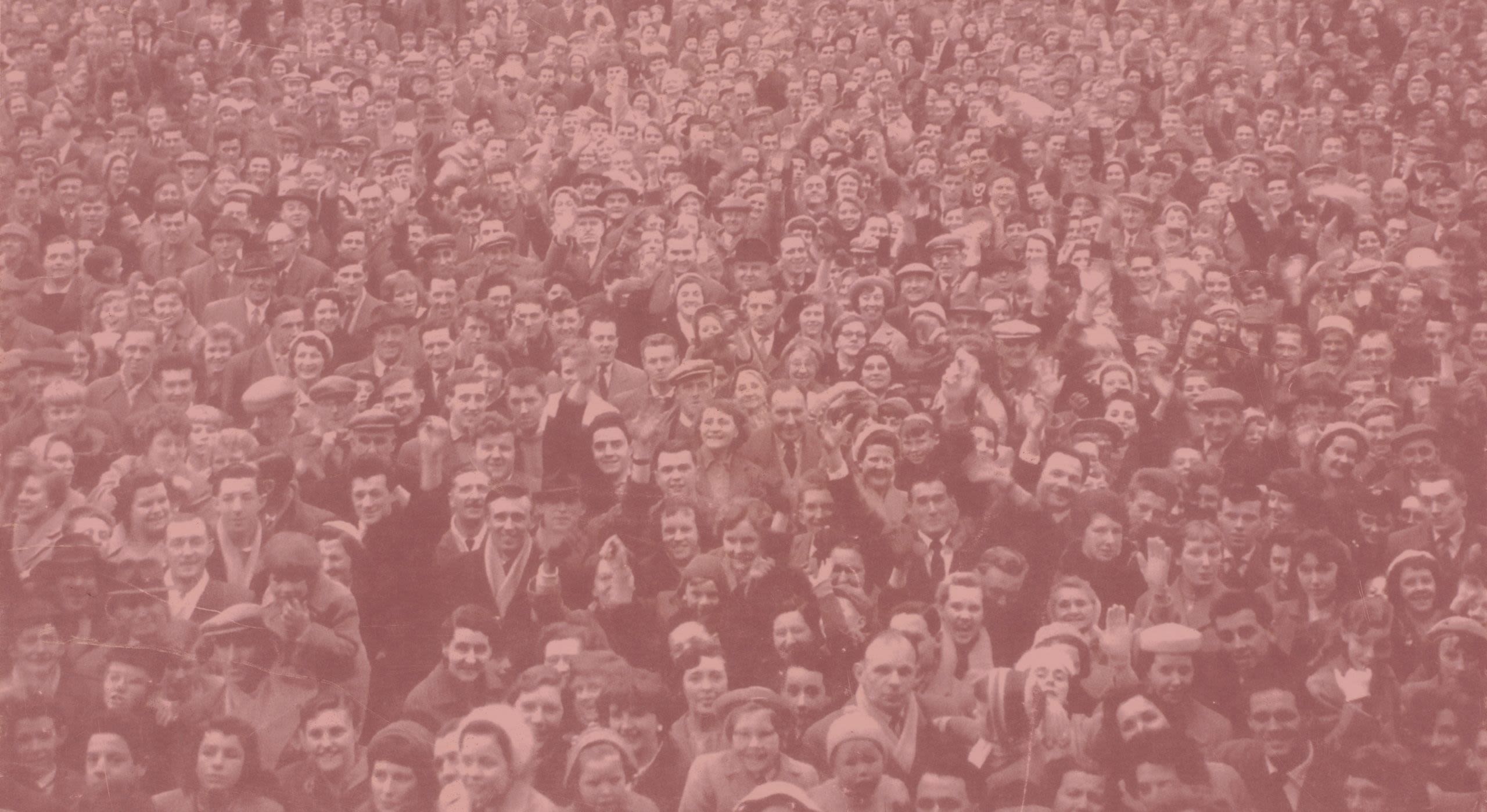 A black and white photo of a large crowd of happy football fans.