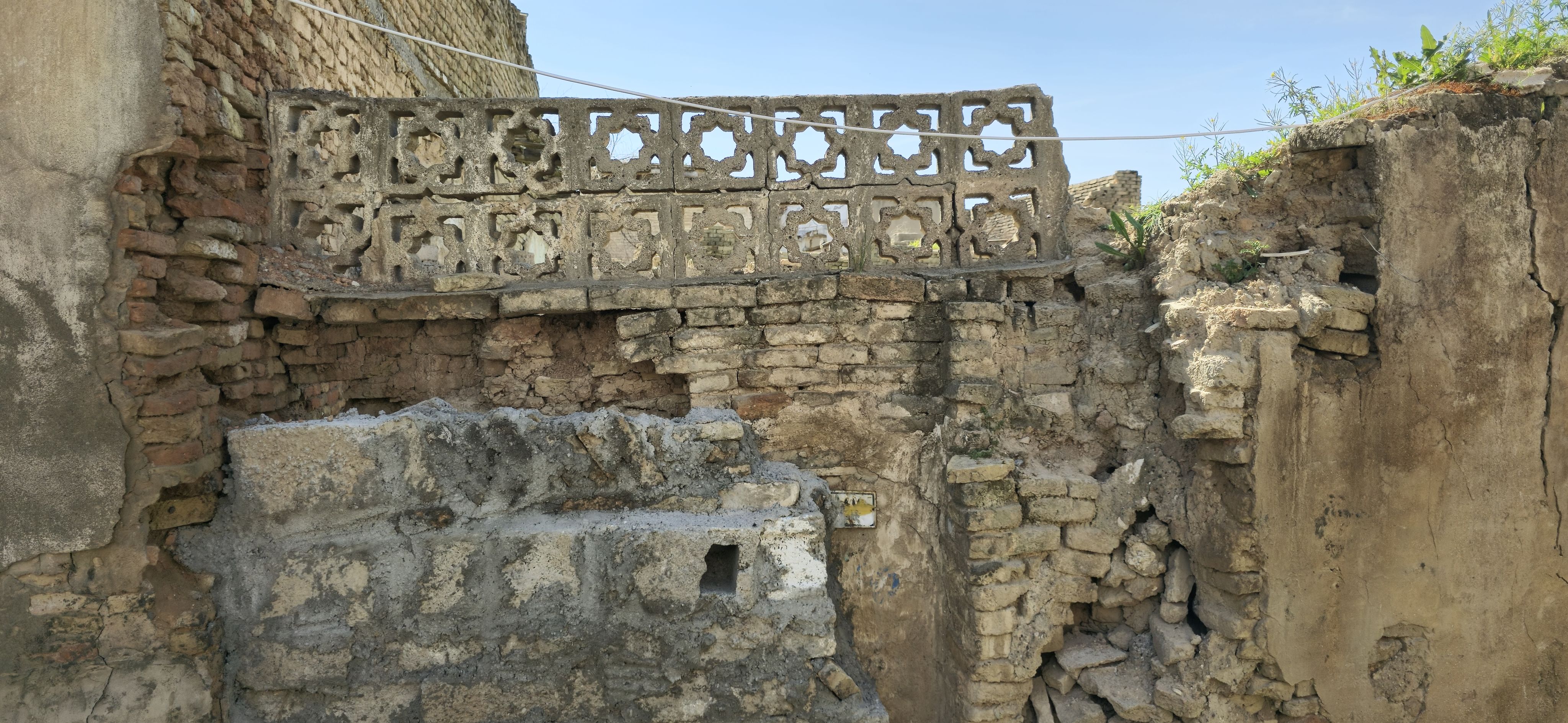 Colour photograph, outdoors, collapsed stone house with openwork decoration.