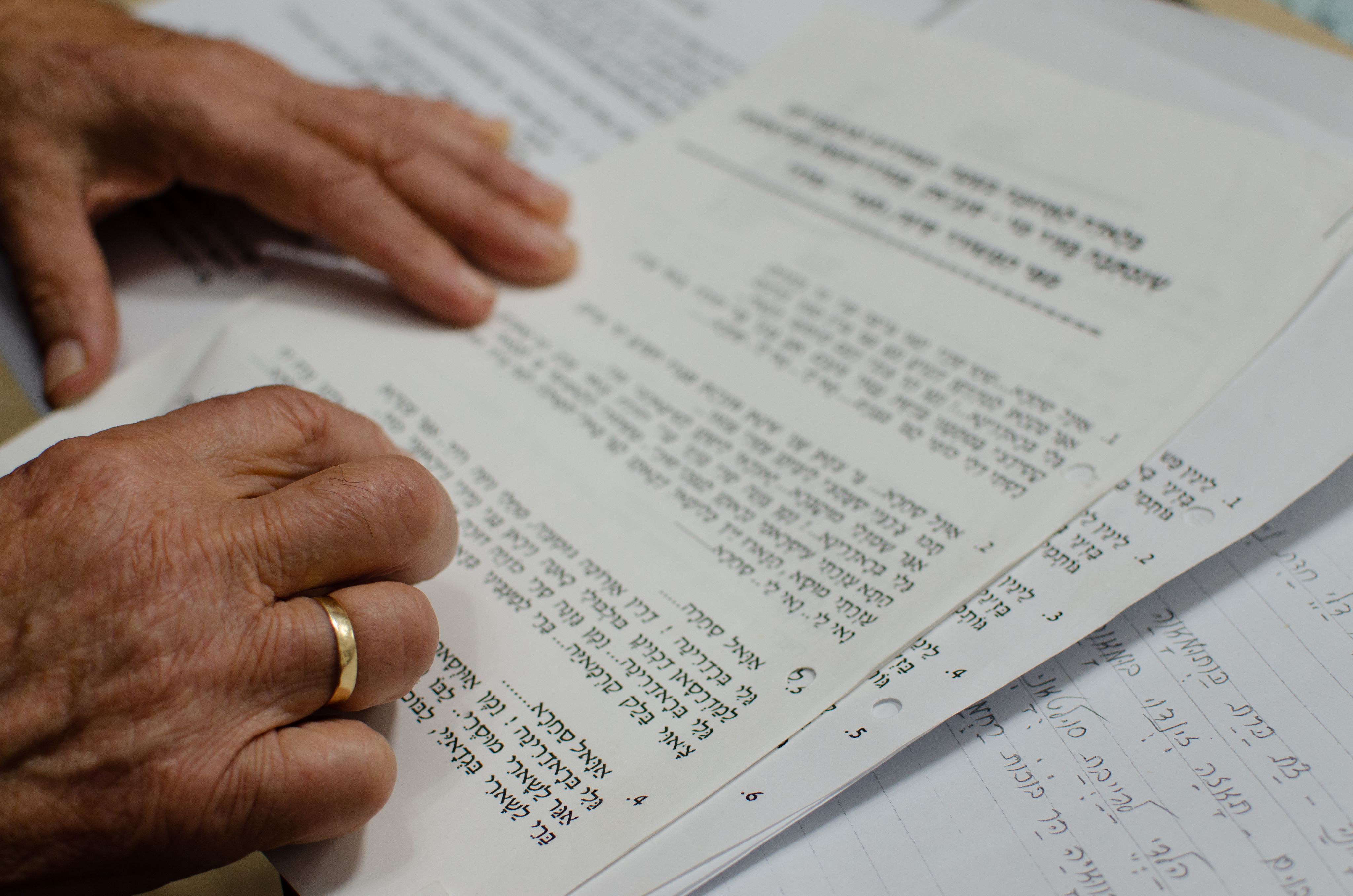 Colour photograph, indoors, some paper with writing on it, two hands pressed to read.