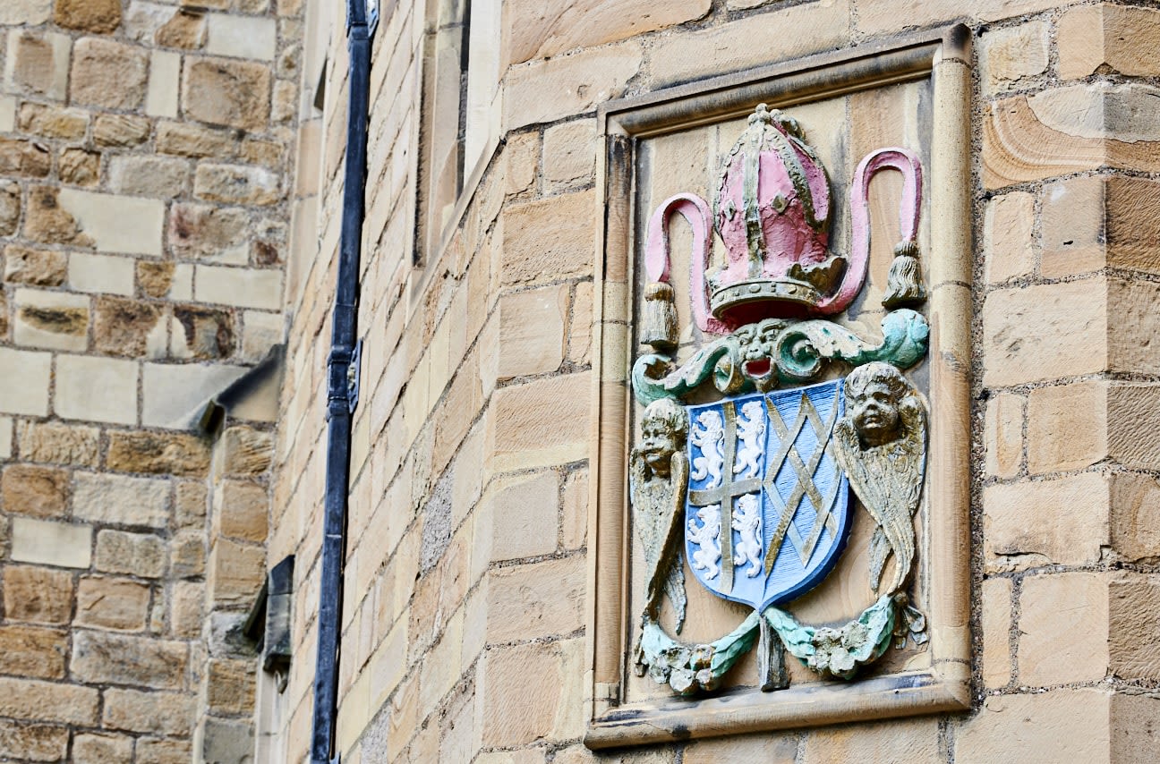 External view of Durham Castle. Close up of a wall showing the crest of Bishop Cosin