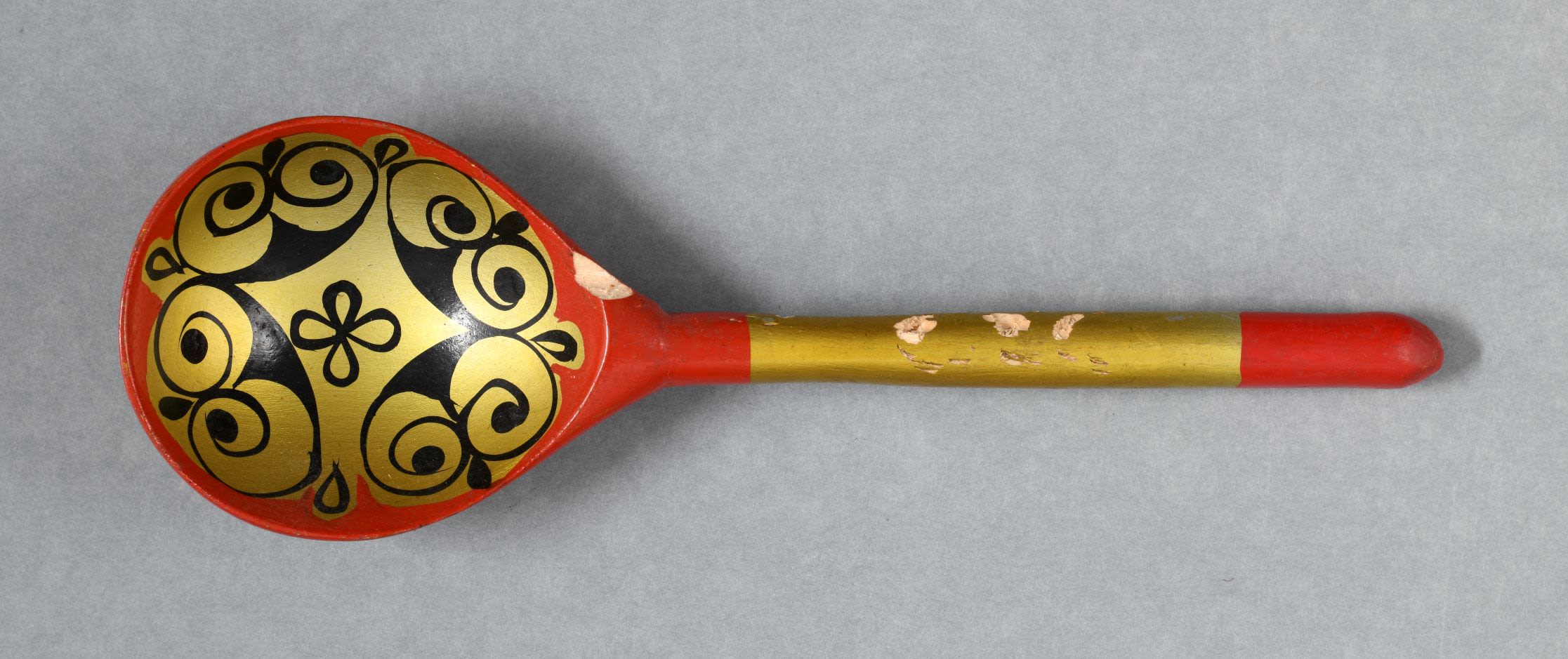 Lacquered wooden spoon painted with floral patterns in gold, red and black.