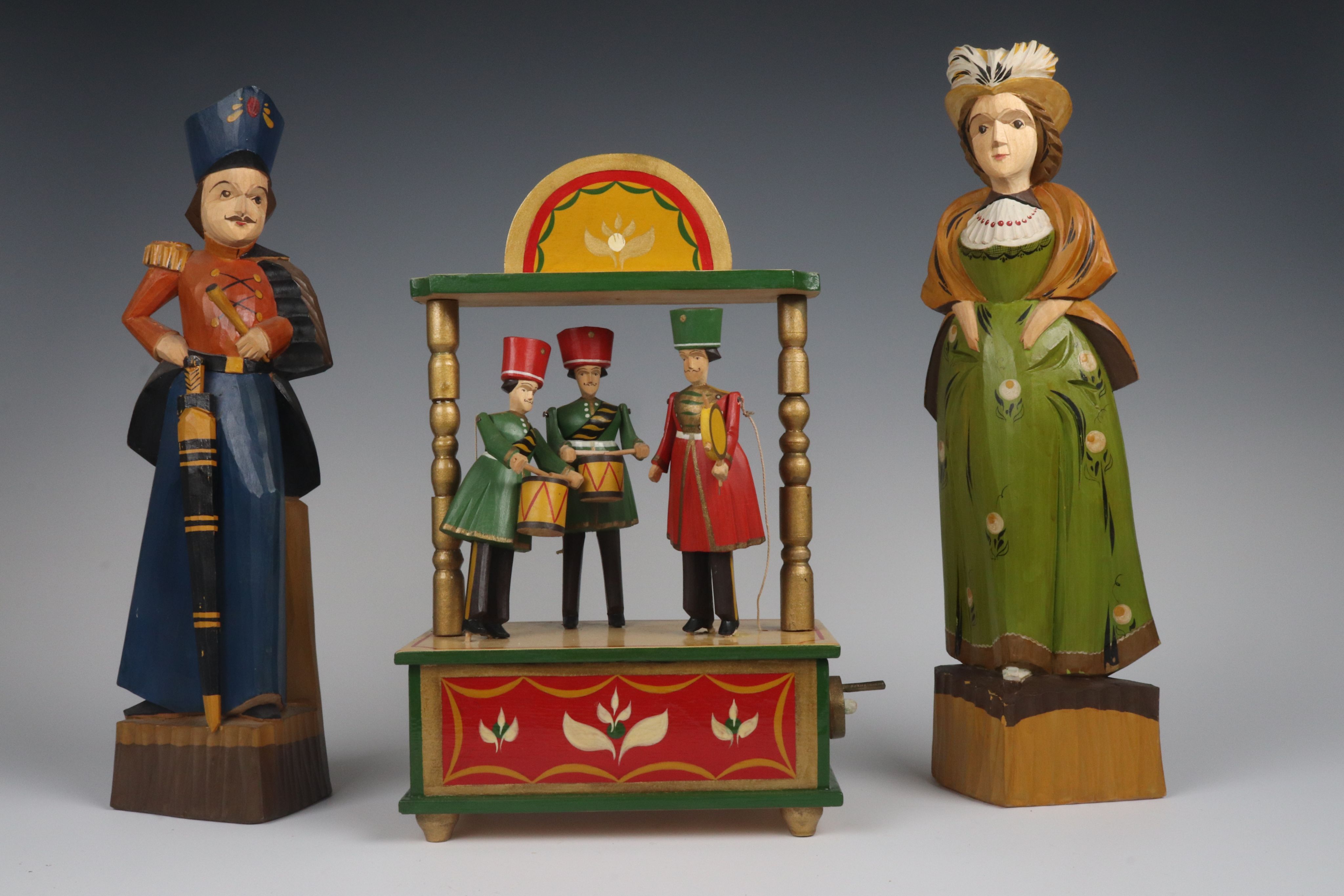 wooden toys: a set depicting a military band and two figures: a man in uniform and a lady with typical town clothes.