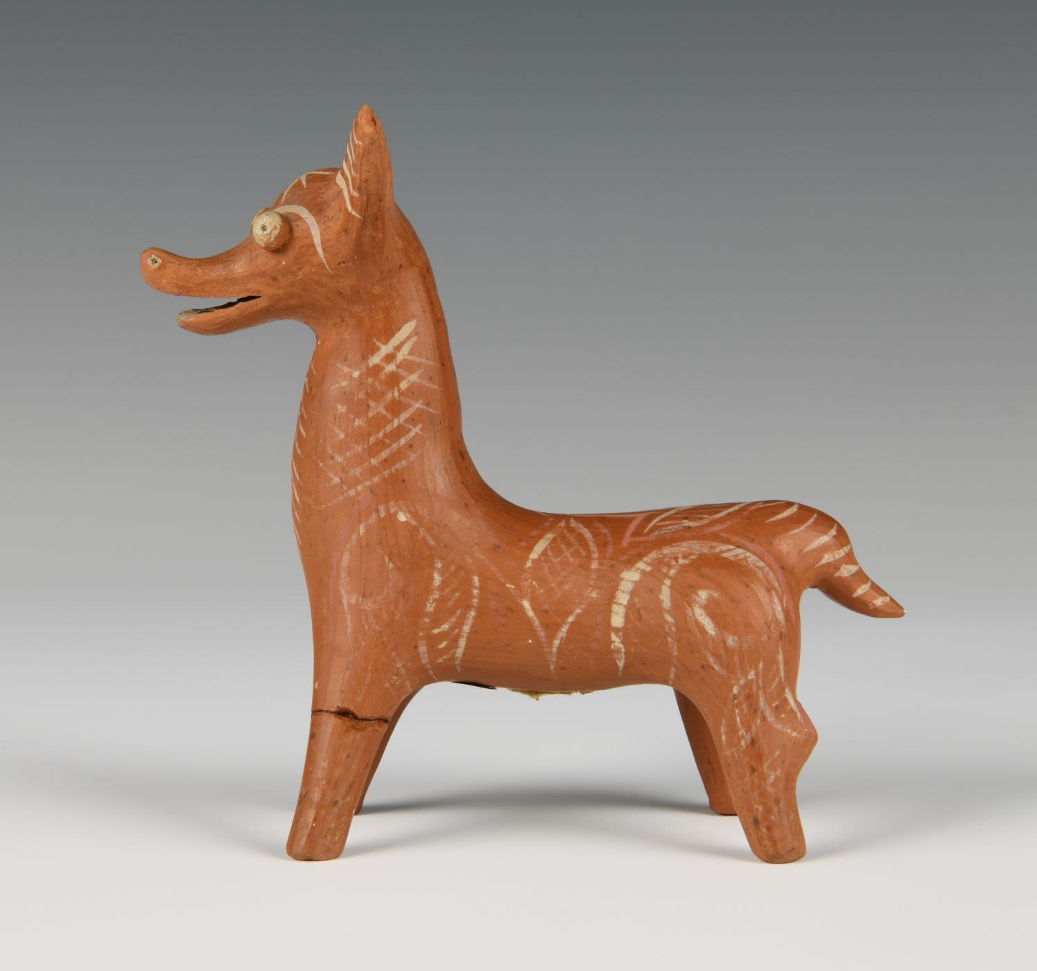 Animal clay toy that stands on four short legs. The body has a slim trunk with a short tail. The figure is decorated with white geometric patterns.