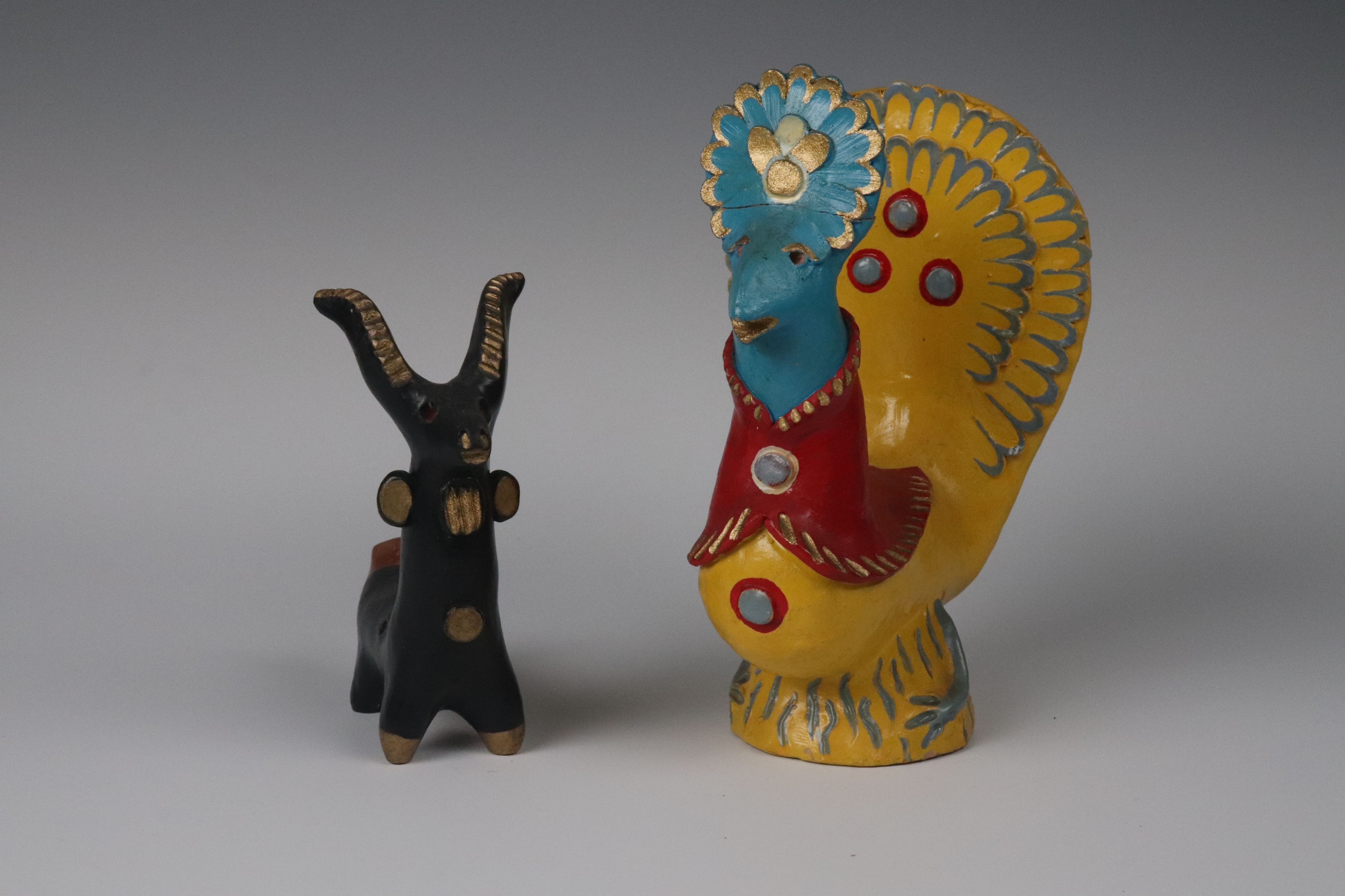 clay toys: black goat with horns and a golden cockrel with a peacock tail.