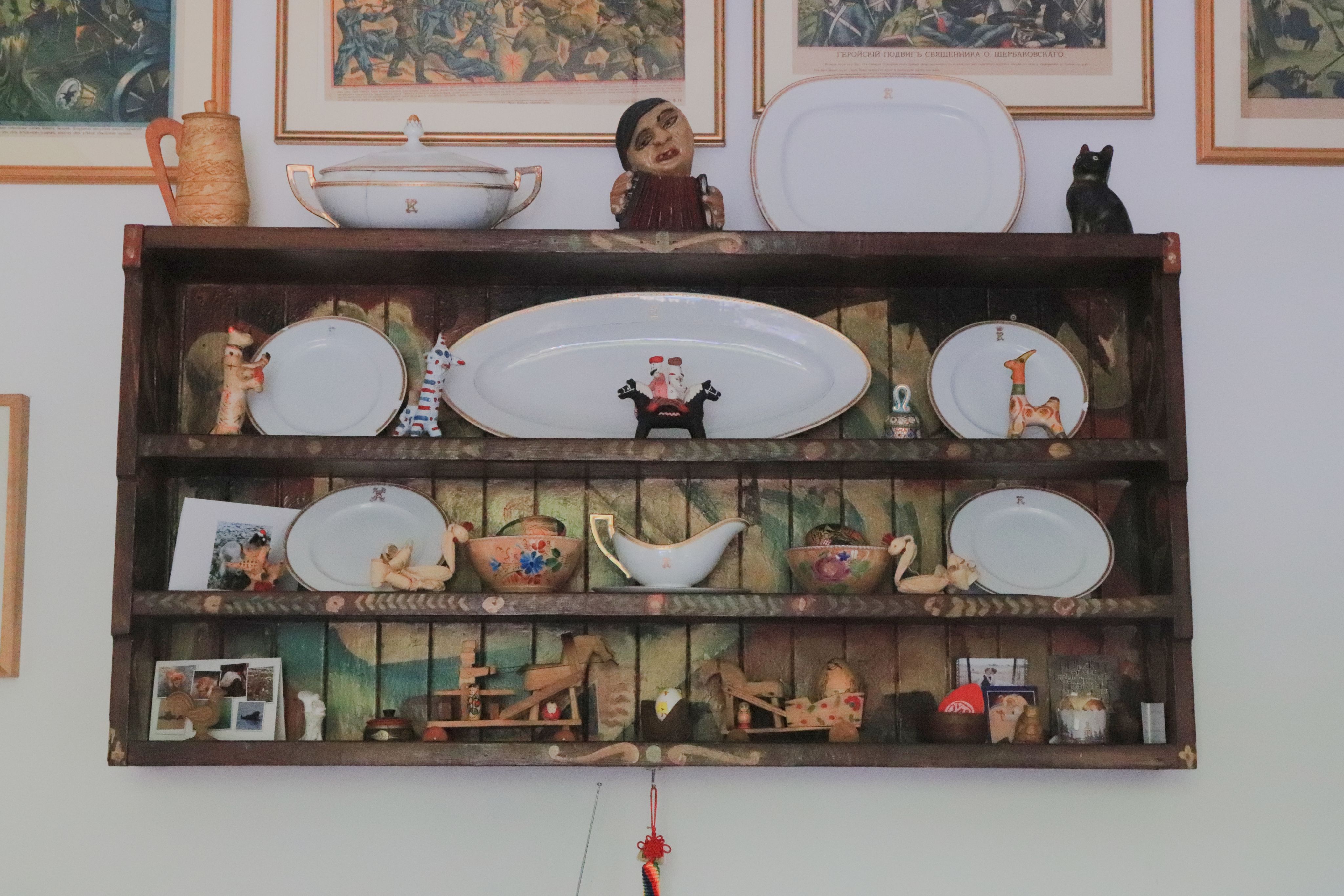 Photograph of a wooden shelf with figures and plates on it.
