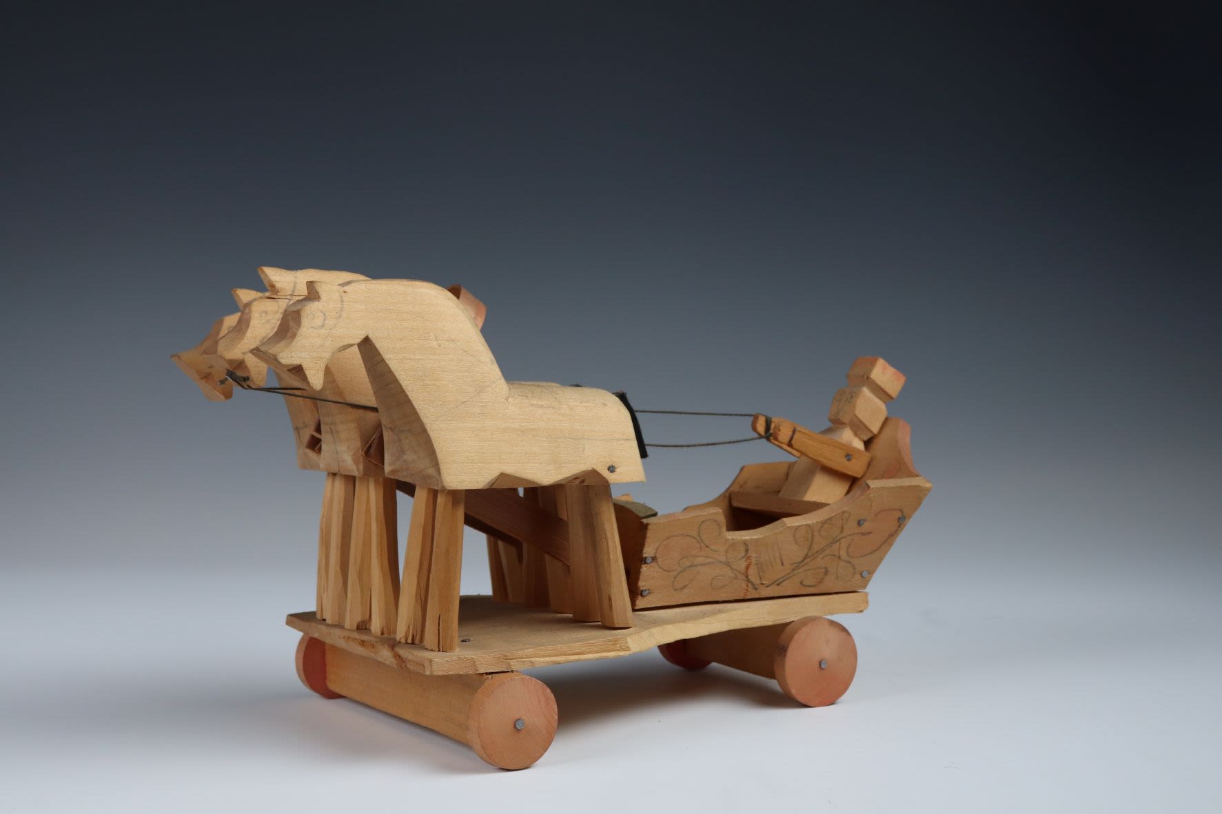 Wooden sledge with horses and driver hand carved and nailed together on wheels.