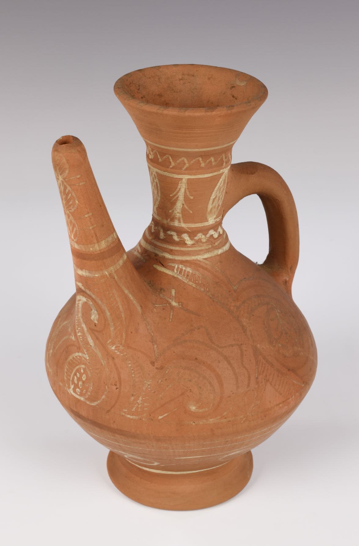 Balkhar jug. The slender jug of light brown earthenware with narrow neck and round body tapering to a small foot. Although it is left unpainted the jug is decorated with traditional Balkhar ornament of white and red.