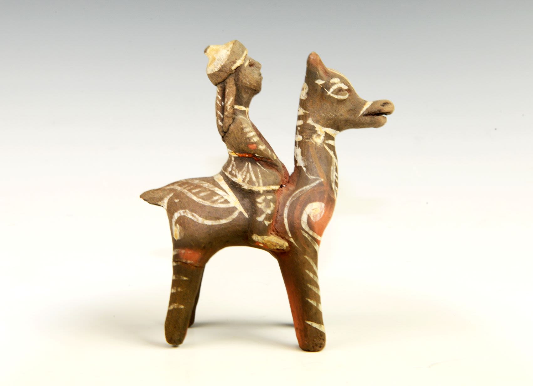 Balkhar toy of a rider on an animal that is possibly an antelope. The animal stands on four widely spread long legs.