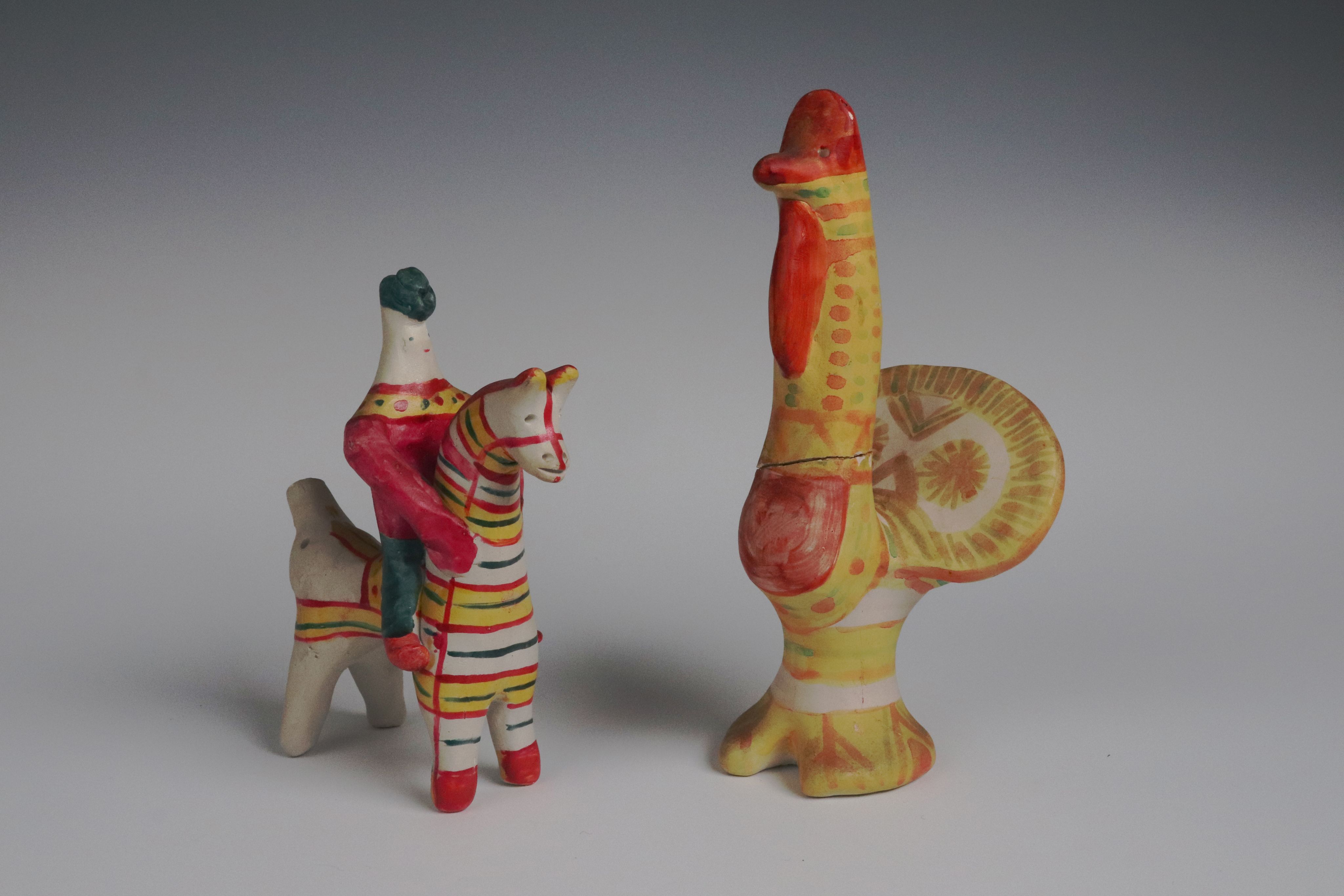 clay toys: a man on a horse and a turkey. They are decorated with yellow and red stripes and dots