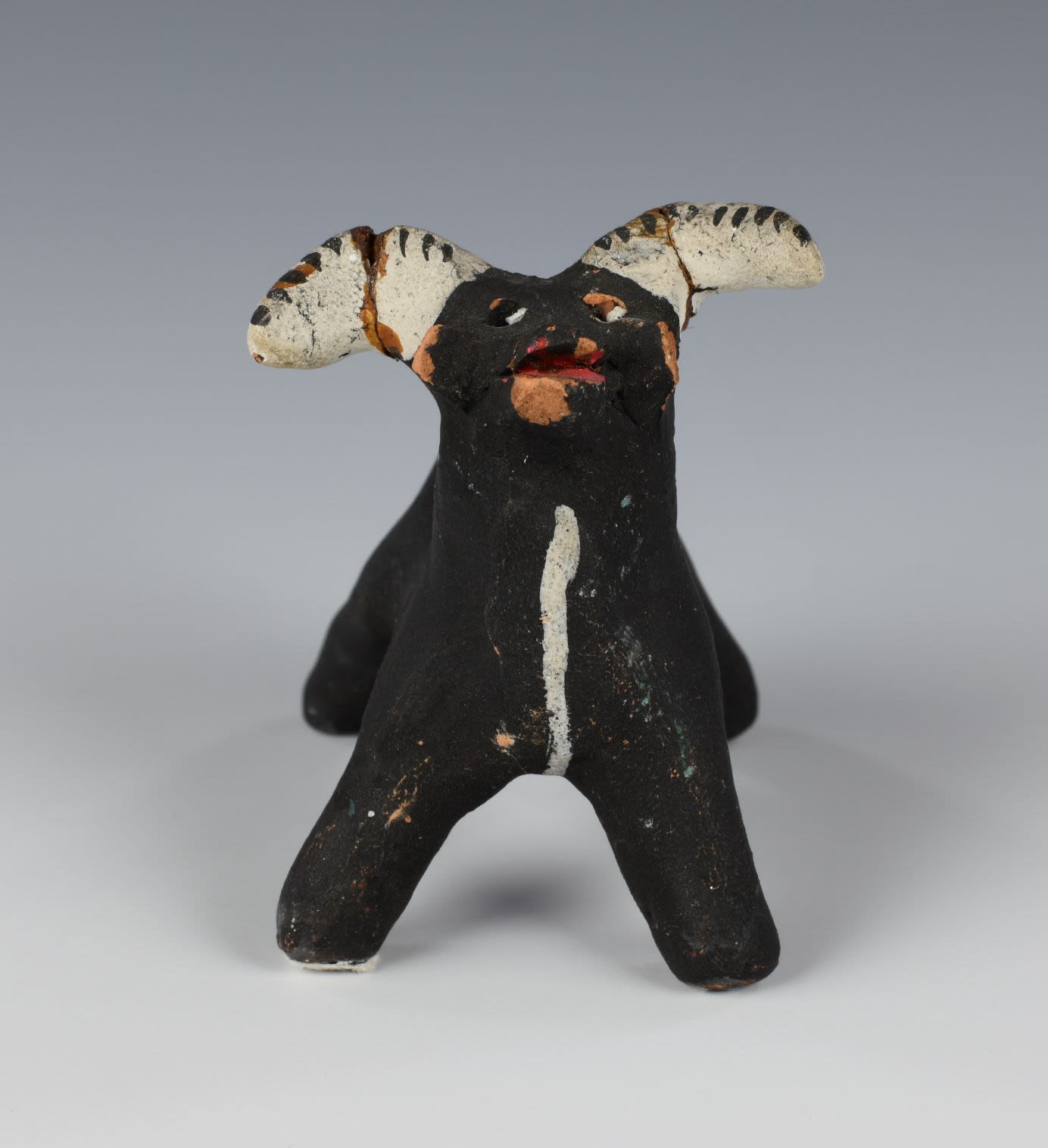 Clay toy in the shape of a cow. The cow is black with white horns.
