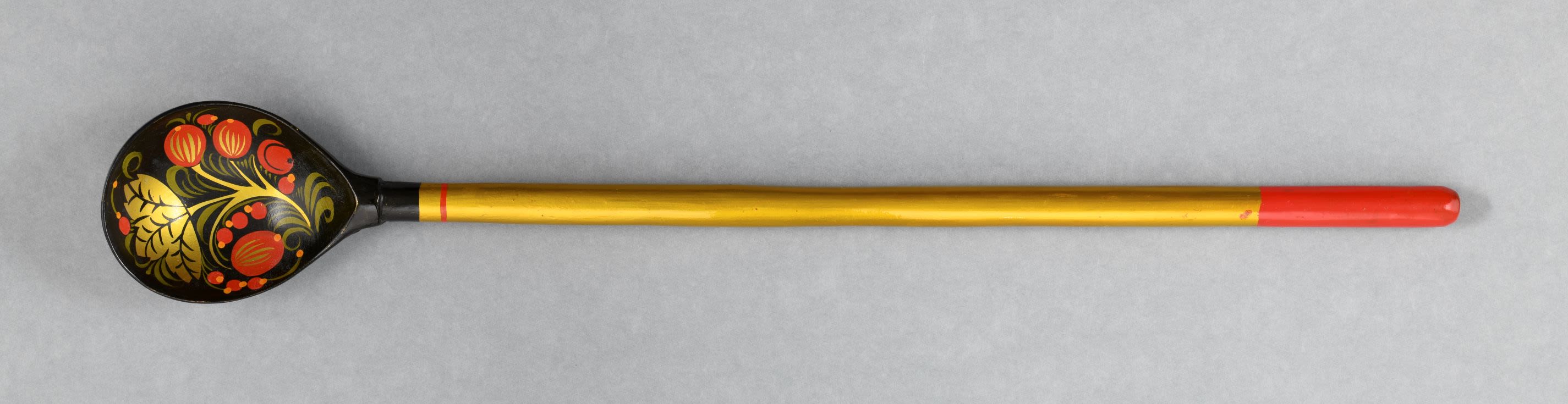 Khokhloma spoon. Lacquered wooden spoon has shallow rounded bowl and a long circular handle is decorated in combination of gold, black, red, green and yellow colours.