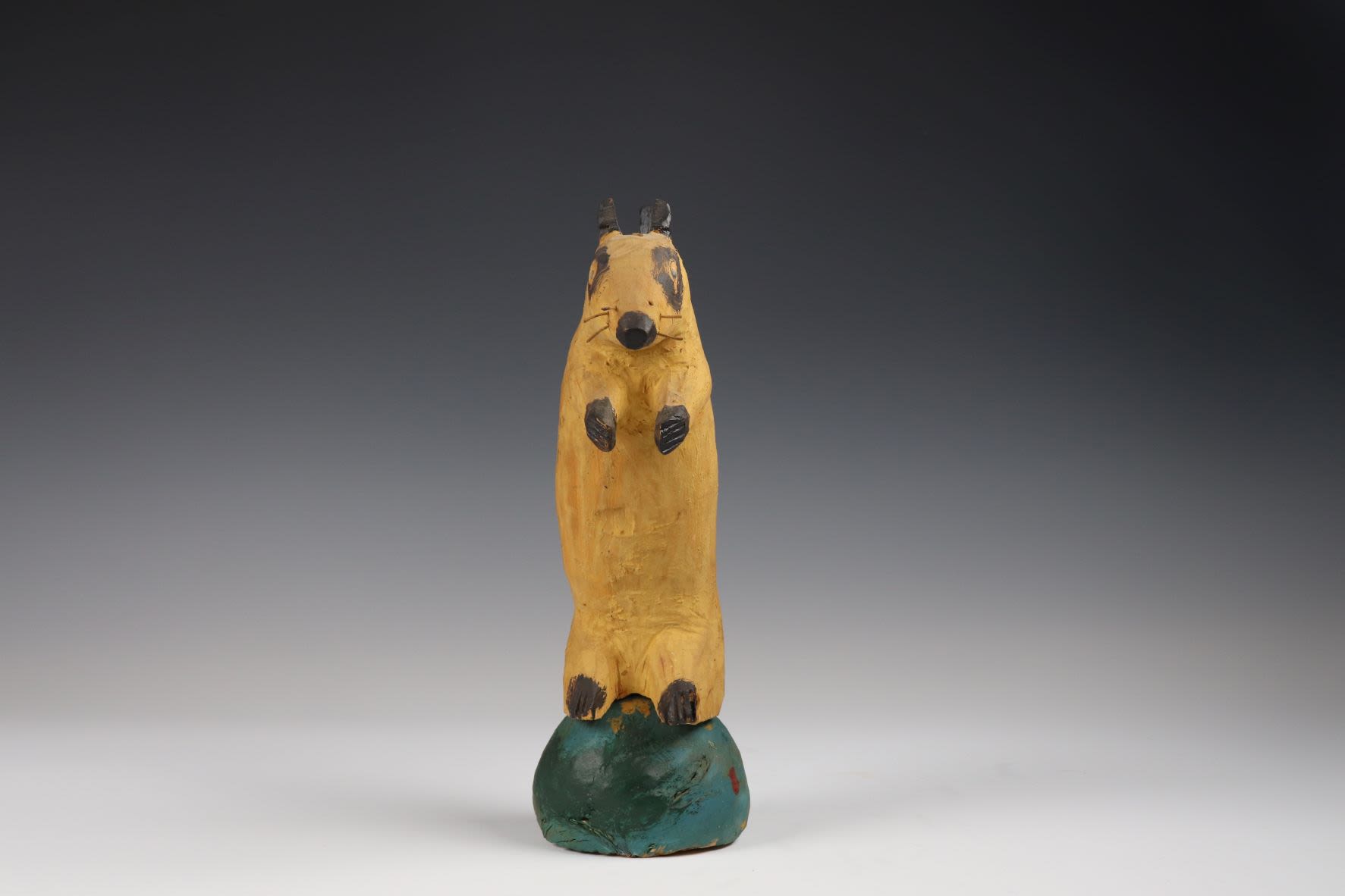 Wooden squirrel roughly carved on a green base leaning forward.