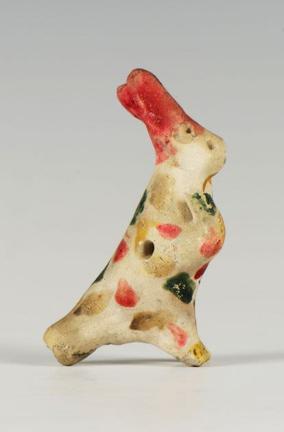 Clay whistle in the shape of a rabbit. The painting pattern consists of splashes of green, red, black and yellow on the unpainted dirty white surface of the figure.