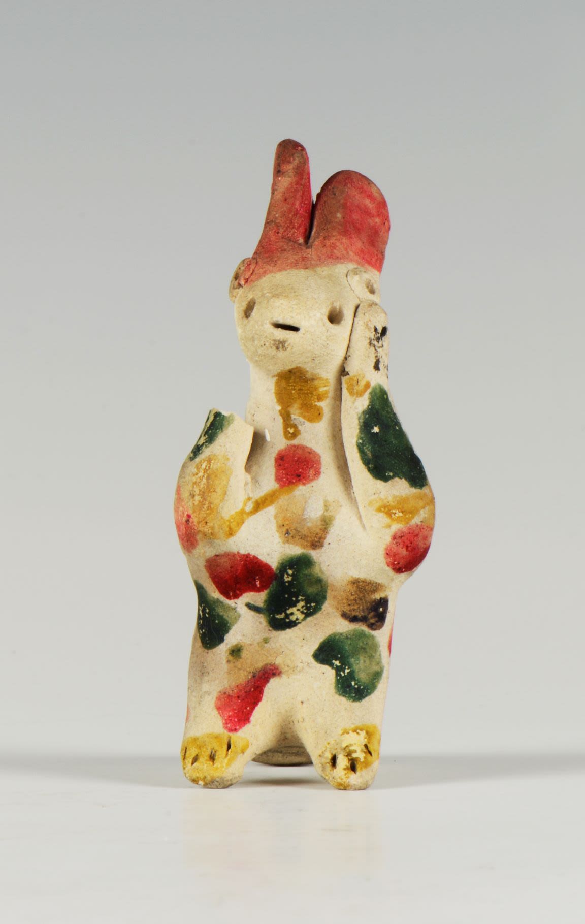 Clay whistle in the shape of a rabbit. The painting pattern consists of green, red, black and yellow on the unpainted white surface of the figure.