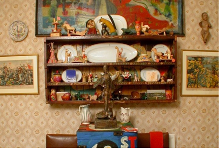 Photograph of a wooden shelf with figures and plates.