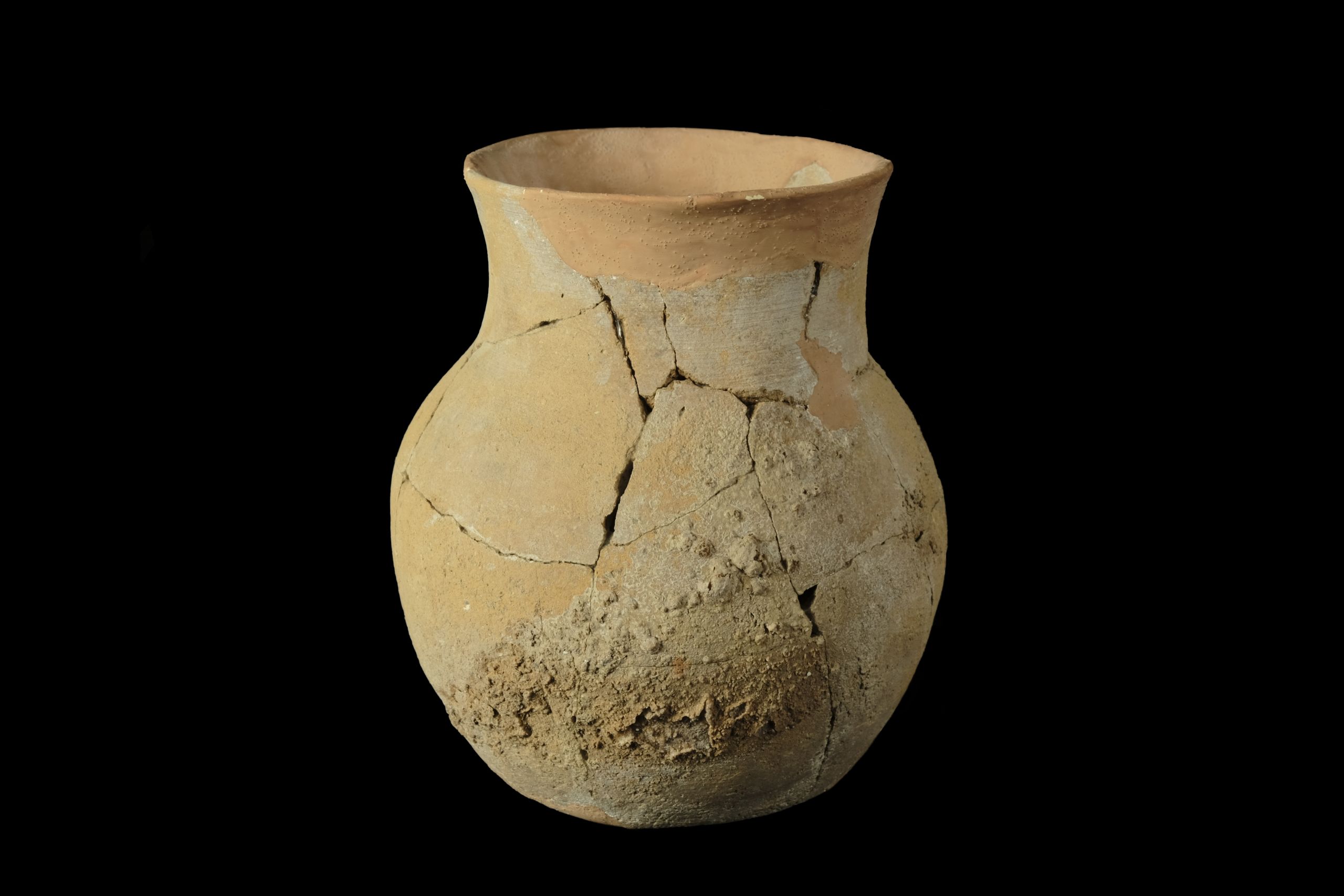 A tall, wide-rimmed pot, reconstructed with orange plaster from many dirt-encrusted sherds