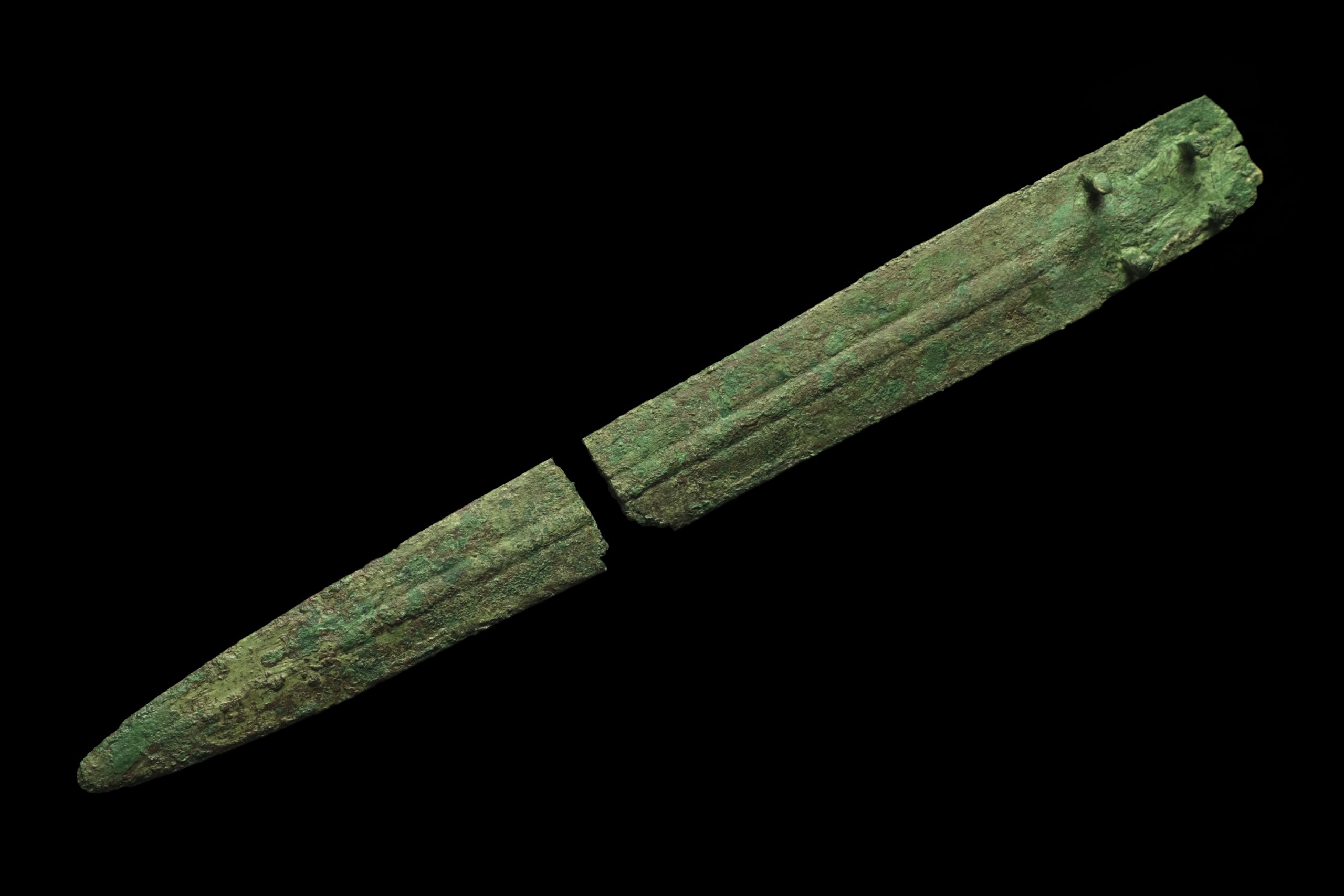 Knife blade with green corrosion. Broken in half. Four nails protrude perpendicular to the blade on each side.