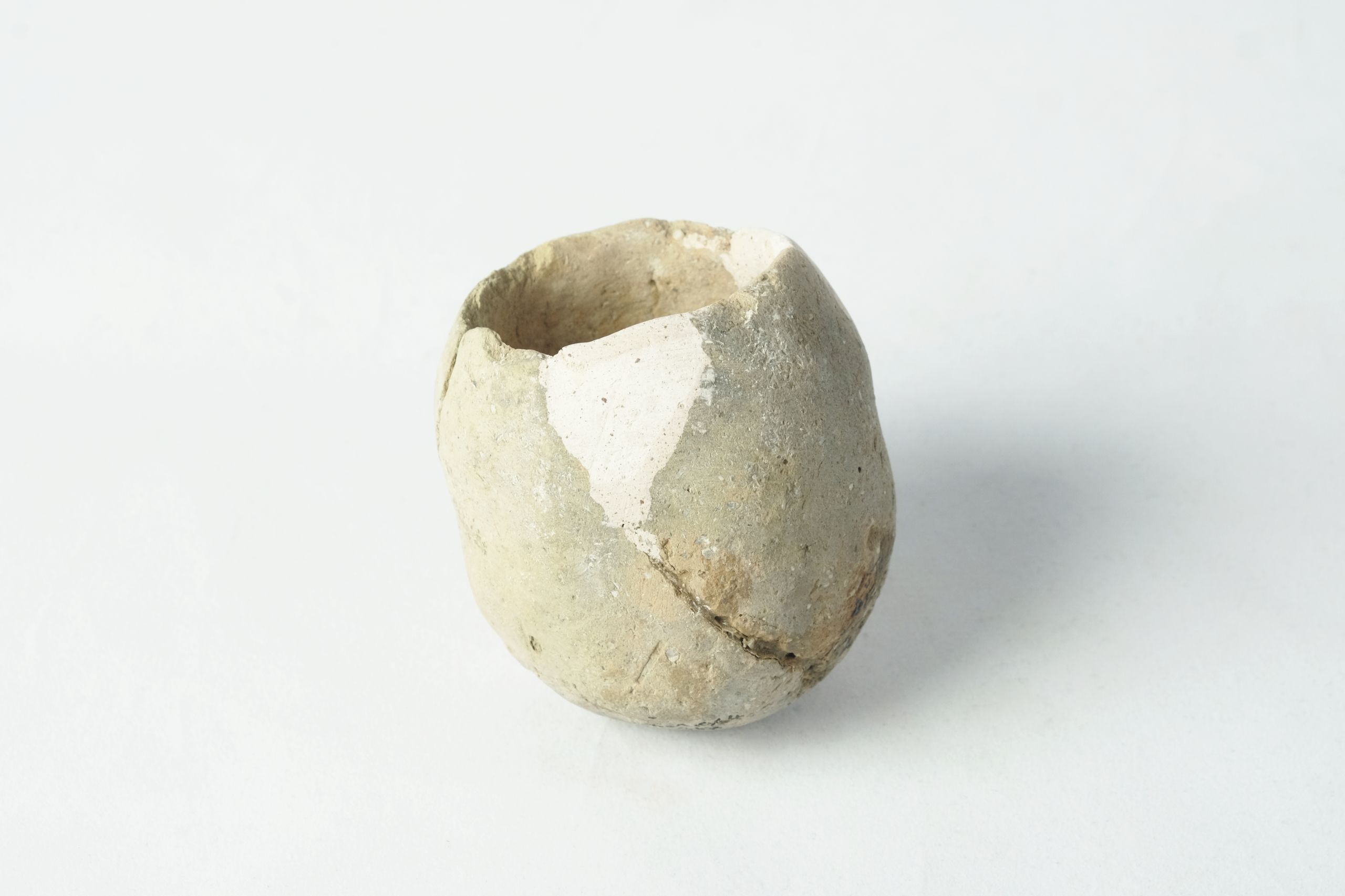 Cup-shaped pot reconstructed with white plaster in between sherds on the body and rim