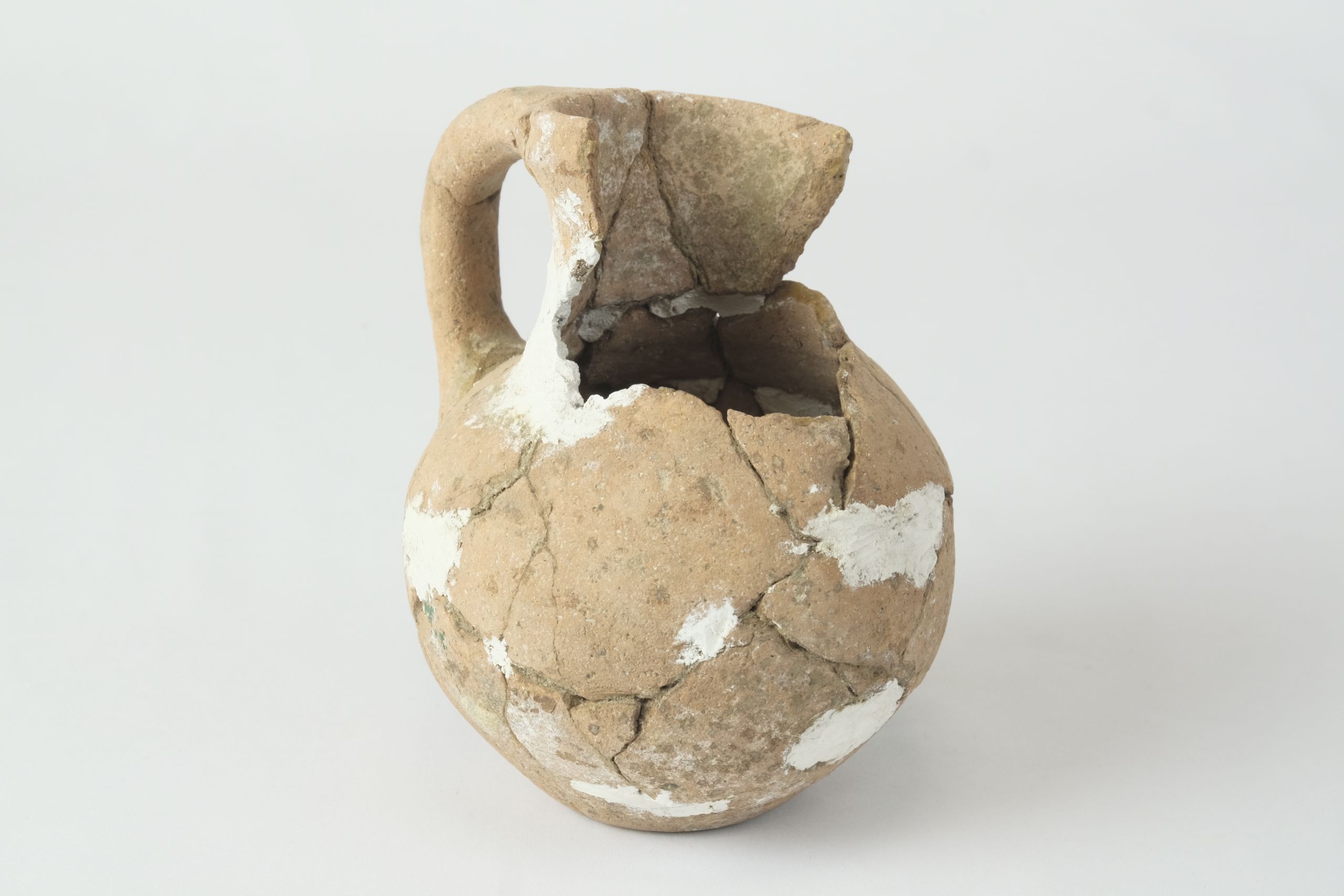 Fragmented jug partially reconstructed with grey plaster on the body