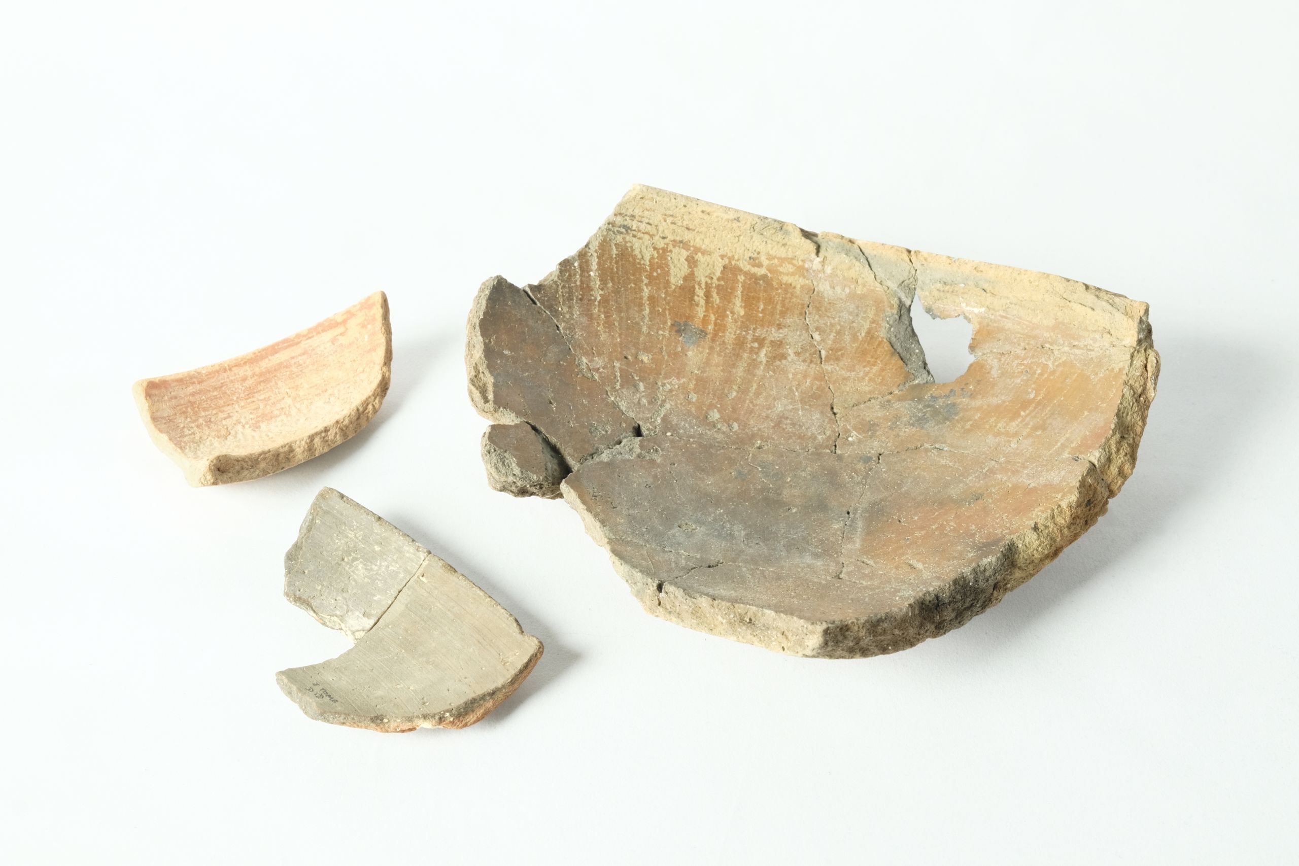 Three fragments of a bowl, including one partially reconstructed base and two smaller rim fragments